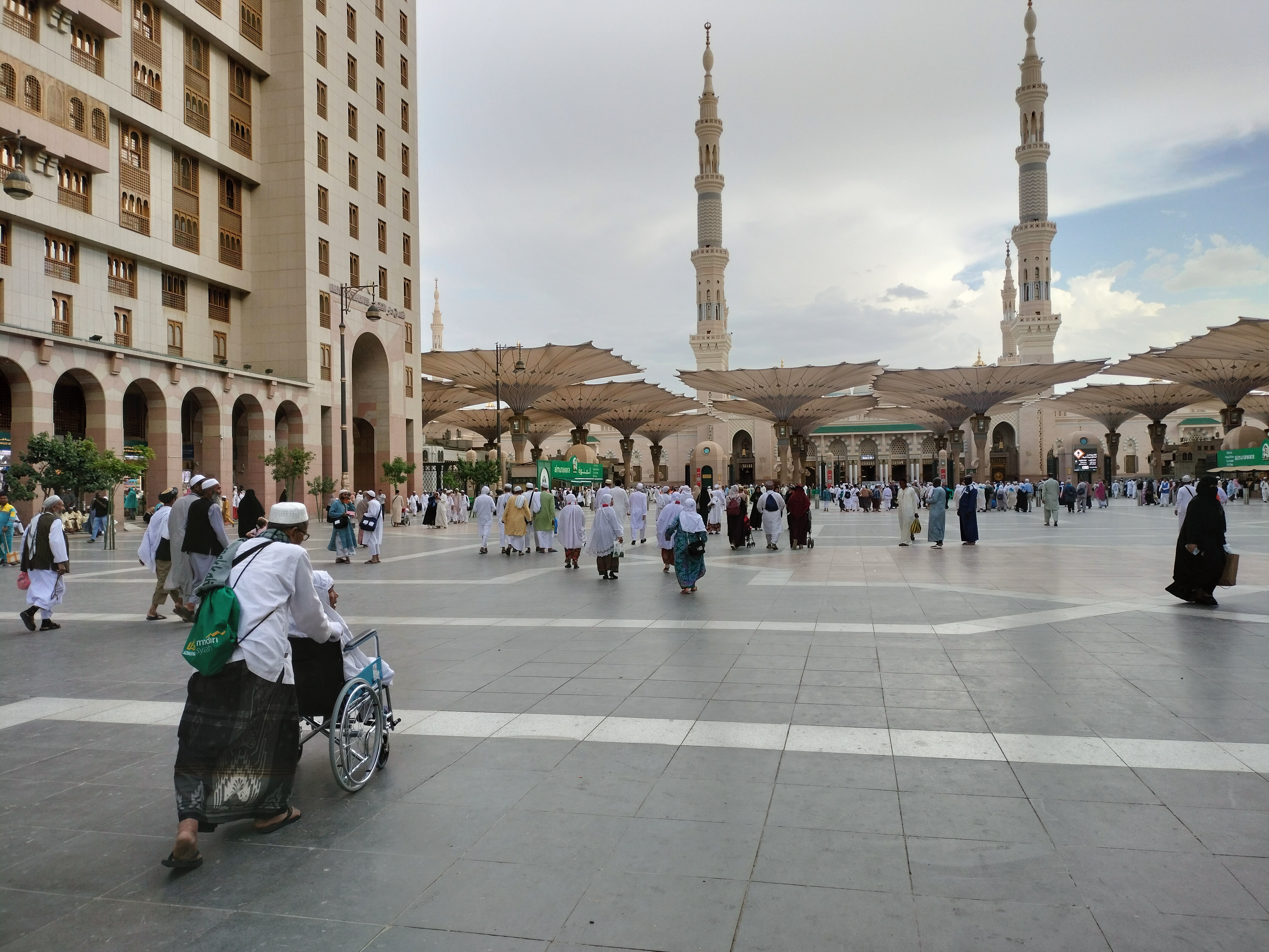 eorang jemaah mendorong jemaah haji berkursi roda menuju Masjid Nabawi, Madinah, Arab Saudi.