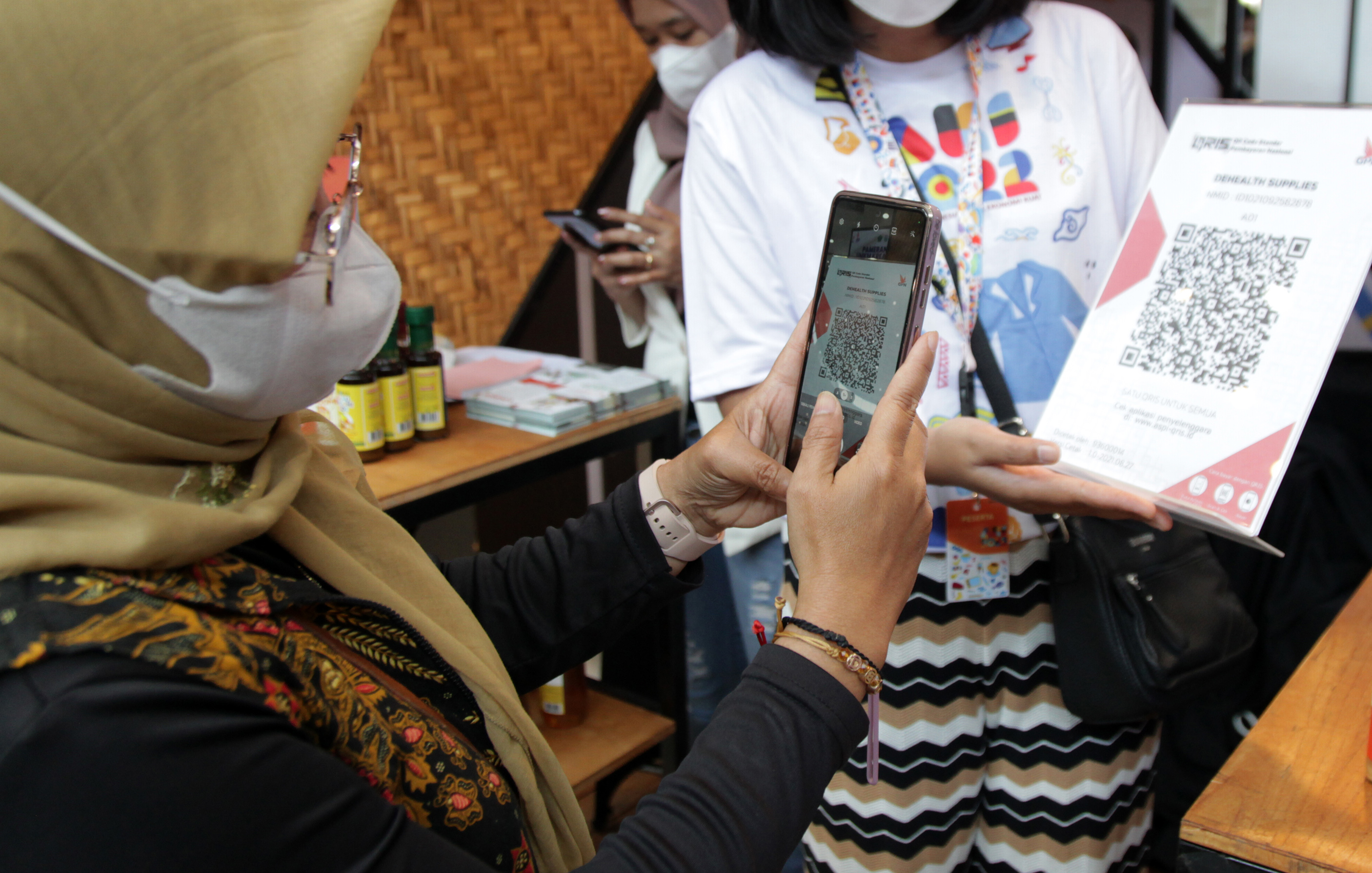 Penjual melayani pembeli melakukan pembayaran digital via QRIS saat pembelian produk UMKM.