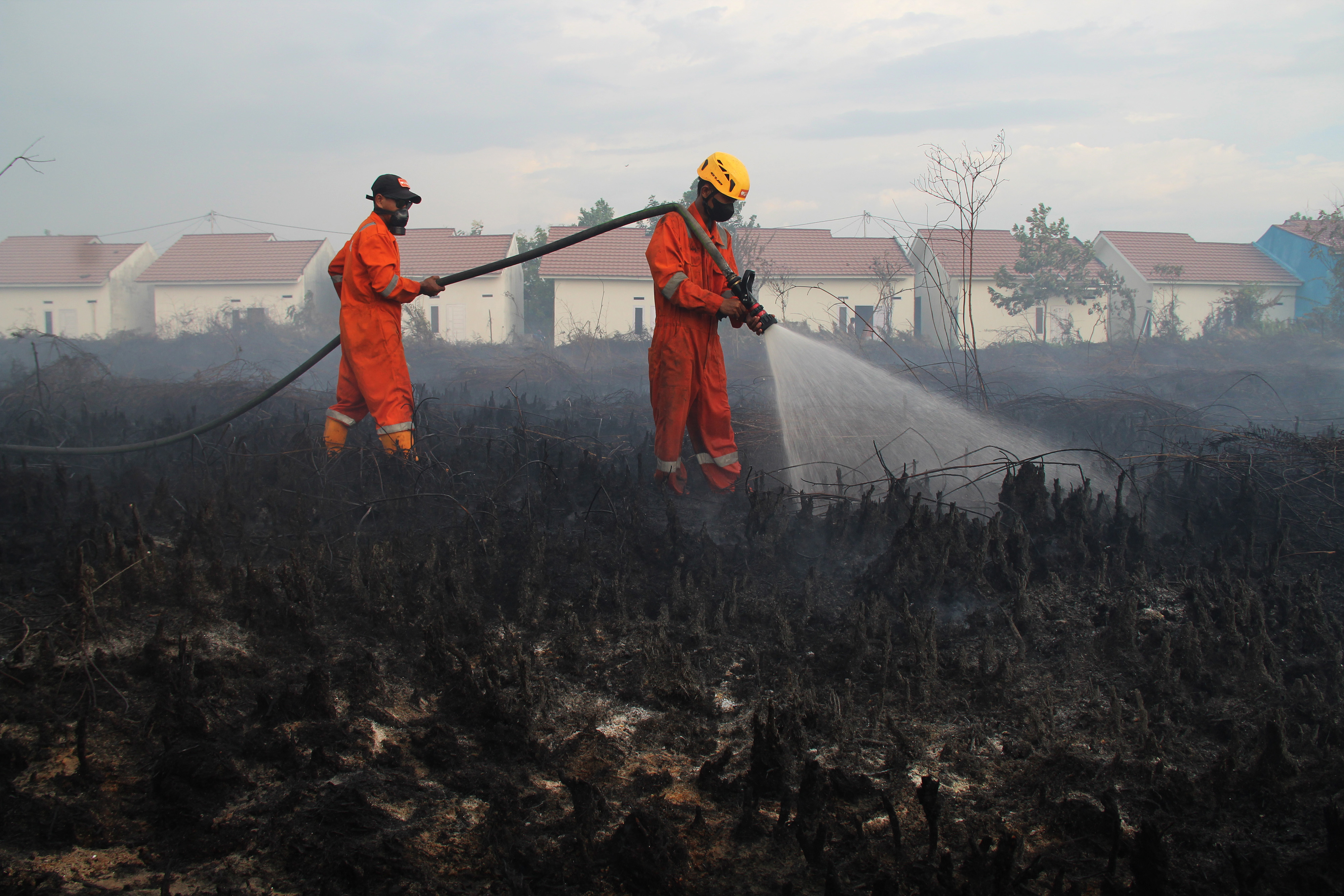 Dua petugas pemadam kebakaran melakukan pembasahan pada lokasi kebakaran hutan dan lahan (karhutla) di Kalimantan Barat.