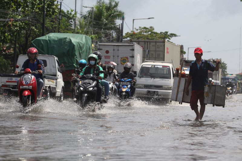 Sejumlah pengendara kendaraan bermotor melintasi banjir rob di Jalan Kalianak, Surabaya, Jawa Timur.