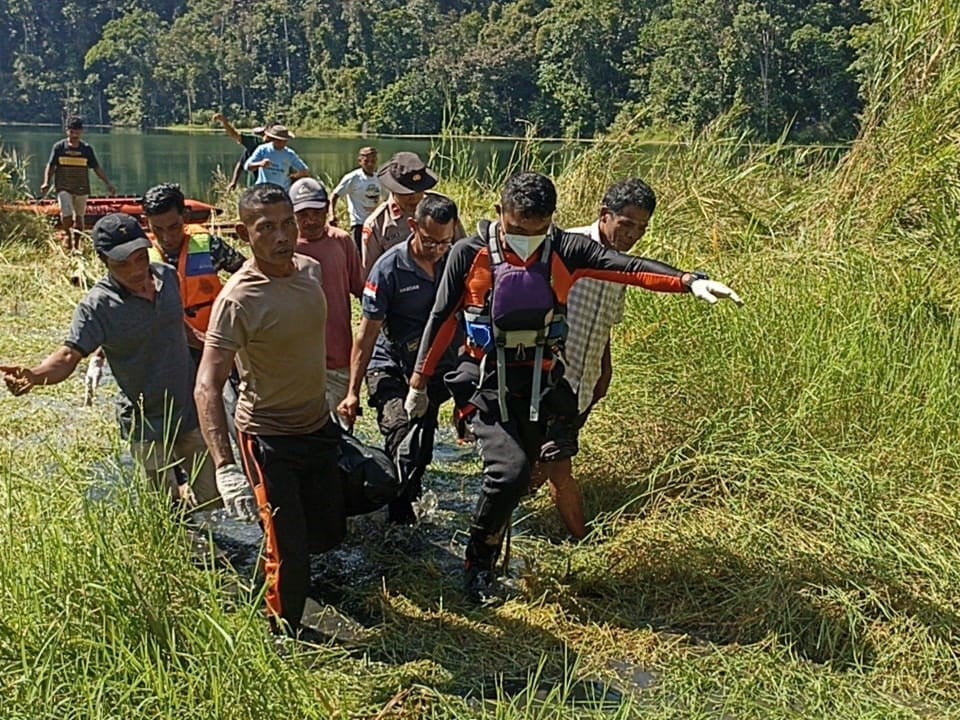 Petugas dibantu warga mengevakuasi jenazah Arsenius Rusman yang tenggelam di danau Rana Kulan.