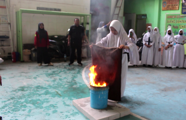 Seorang siswi SMP Muttaqien, Kebon Baru, Tebet, Jakarta Selatan, berlatih memadamkan api menggunakan karung goni basah. 