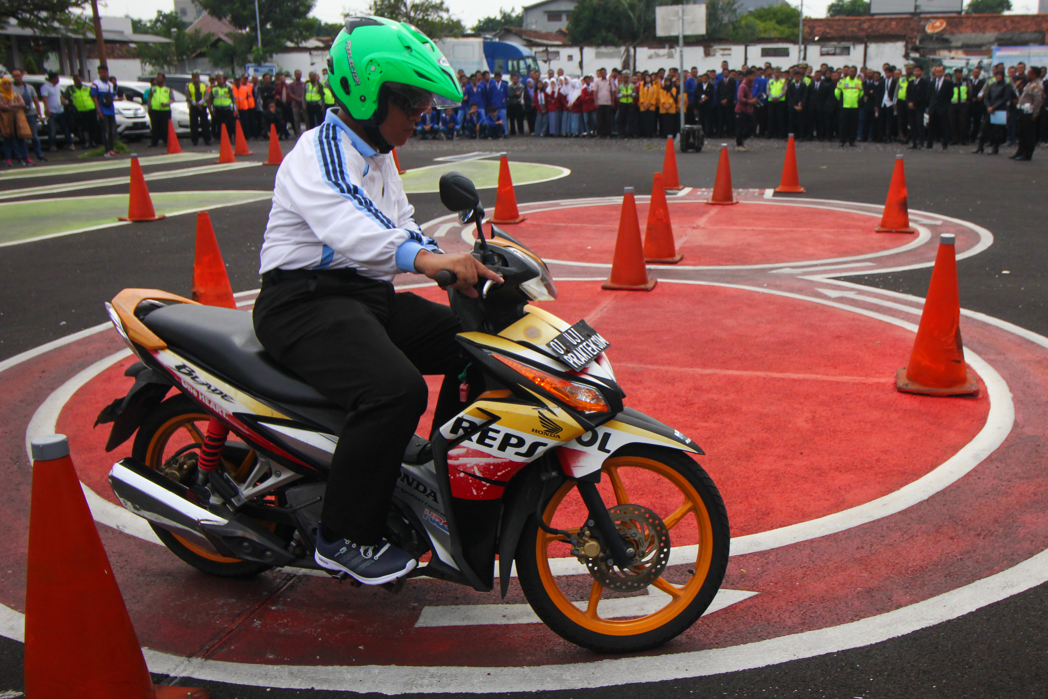 Polisi memberikan contoh cara berkendara motor di area ujian praktek Surat Ijin Mengemudi (SIM) 