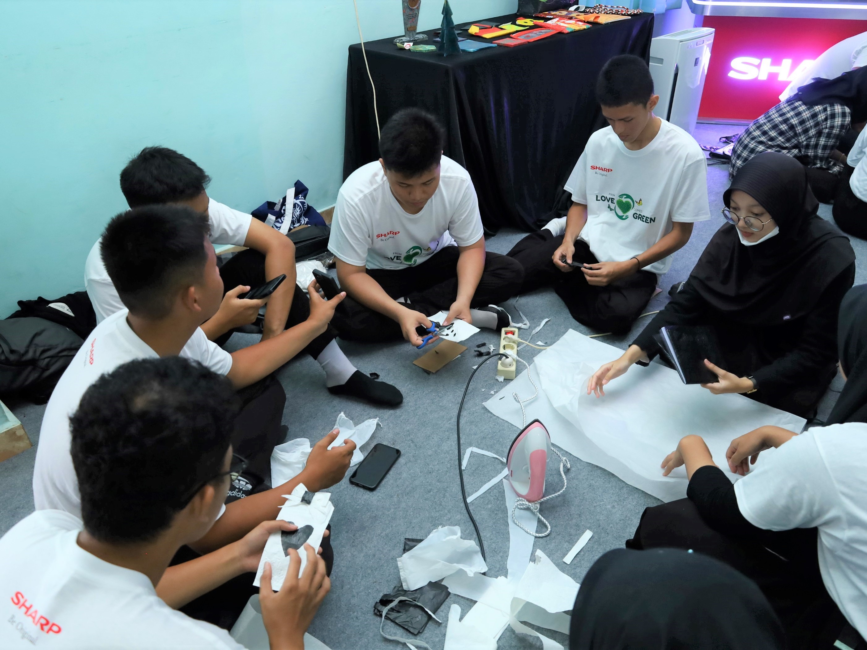 Para siswa SMAN 6 Palembang serta tamu undangan lain melakukan daur ulang limbah plastik menjadi sampul buku, wadah smartphone, dan dompet. 