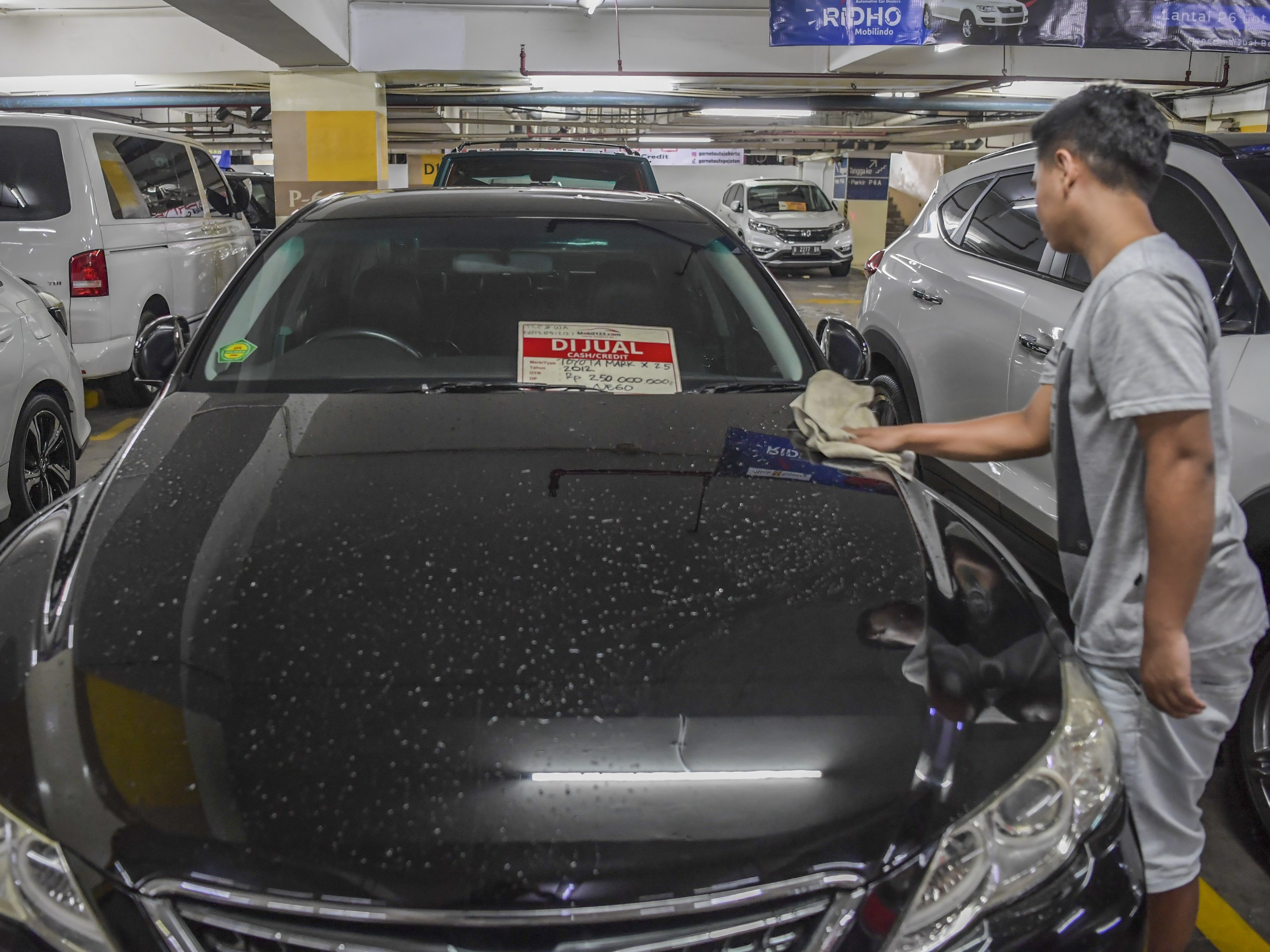 Pedagang mobil bekas membersihkan mobil yang dijual di Gedung Parkir Blok M Square, Jakarta, Jumat (14/4/2023).