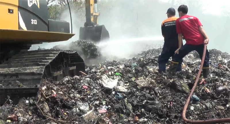 Petugas mengaduk sampah dan menyiramkan air di TPA Darupono untuk menekan gas metana.