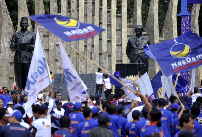 Sejumlah kader dan simpatisan Partai Nasional Demokrat (NasDem) mengibarkan bendera partai pada 2014