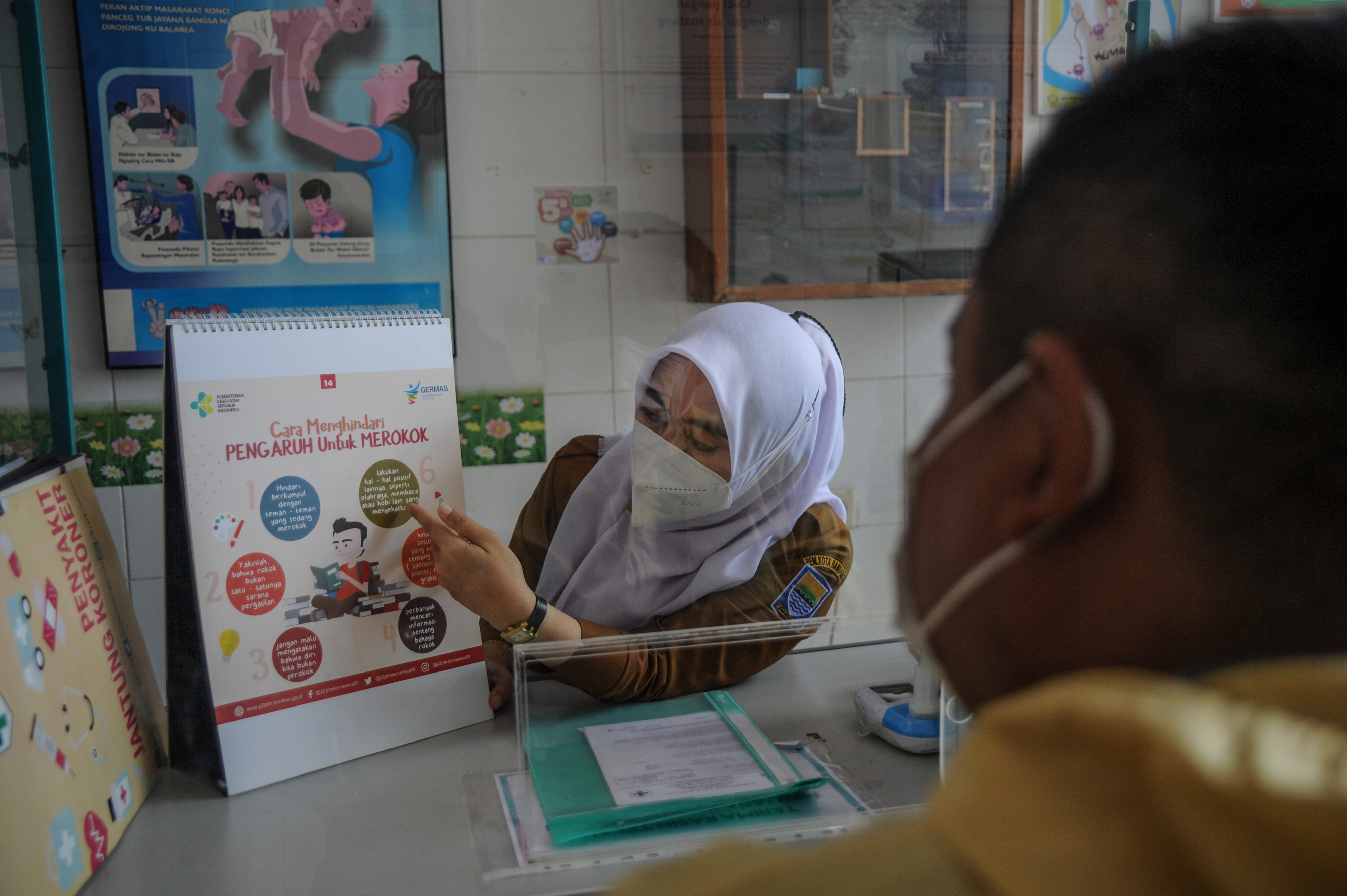 Seorang tenaga kesehatan memberikan konseling berhenti merokok kepada seorang warga di Puskesmas Garuda, Bandung, Jawa Barat.
