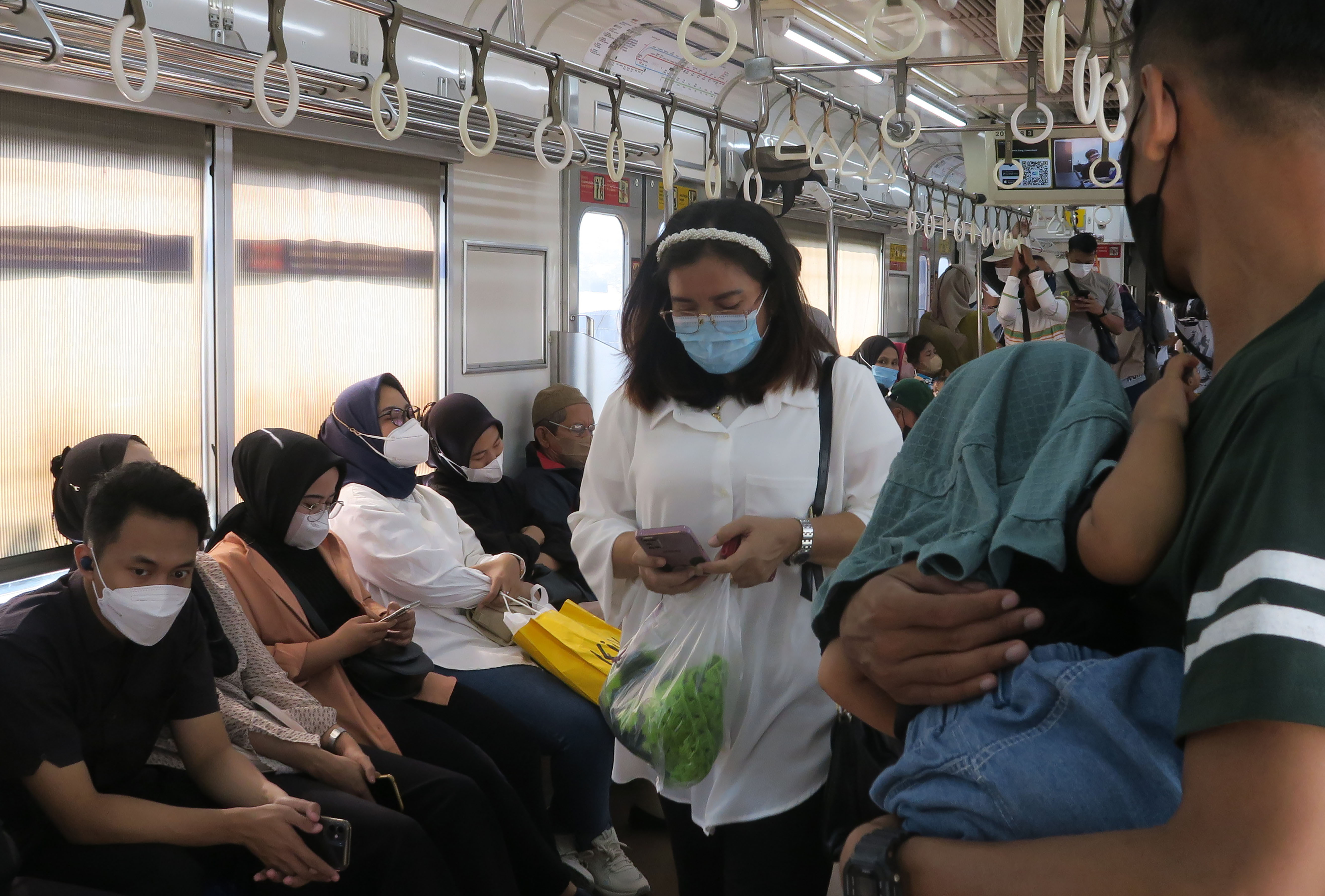 Sejumlah penumpang KRL Commuter line mengenakan masker saat berada di dalam kereta di Stasiun Bekasi Timur, Bekasi