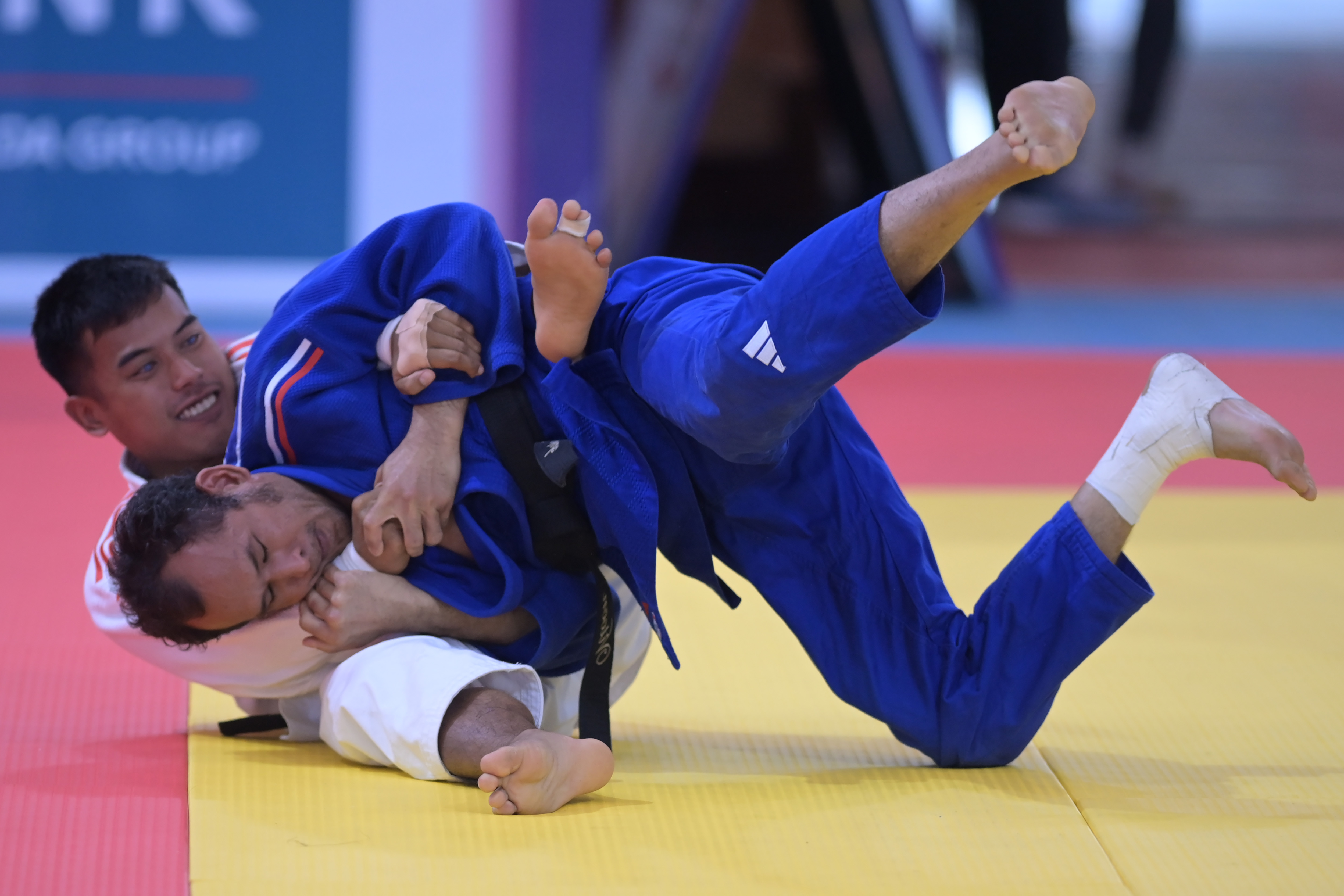 Judoka putra Indonesia Junaedi (atas) berusaha mengunci lawannya judoka Thailand Vitoon Kongsuk (bawah) pada final beregu ASEAN Para Games