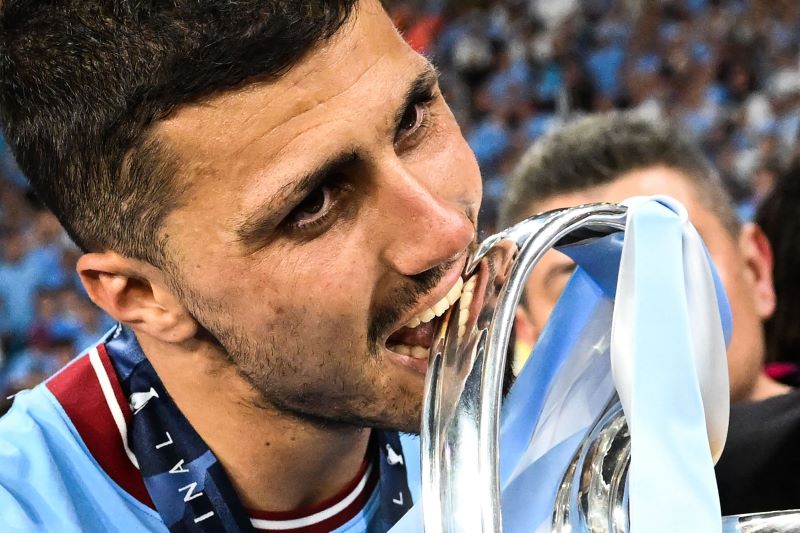 Rodri menggigit trofi Liga Champions.