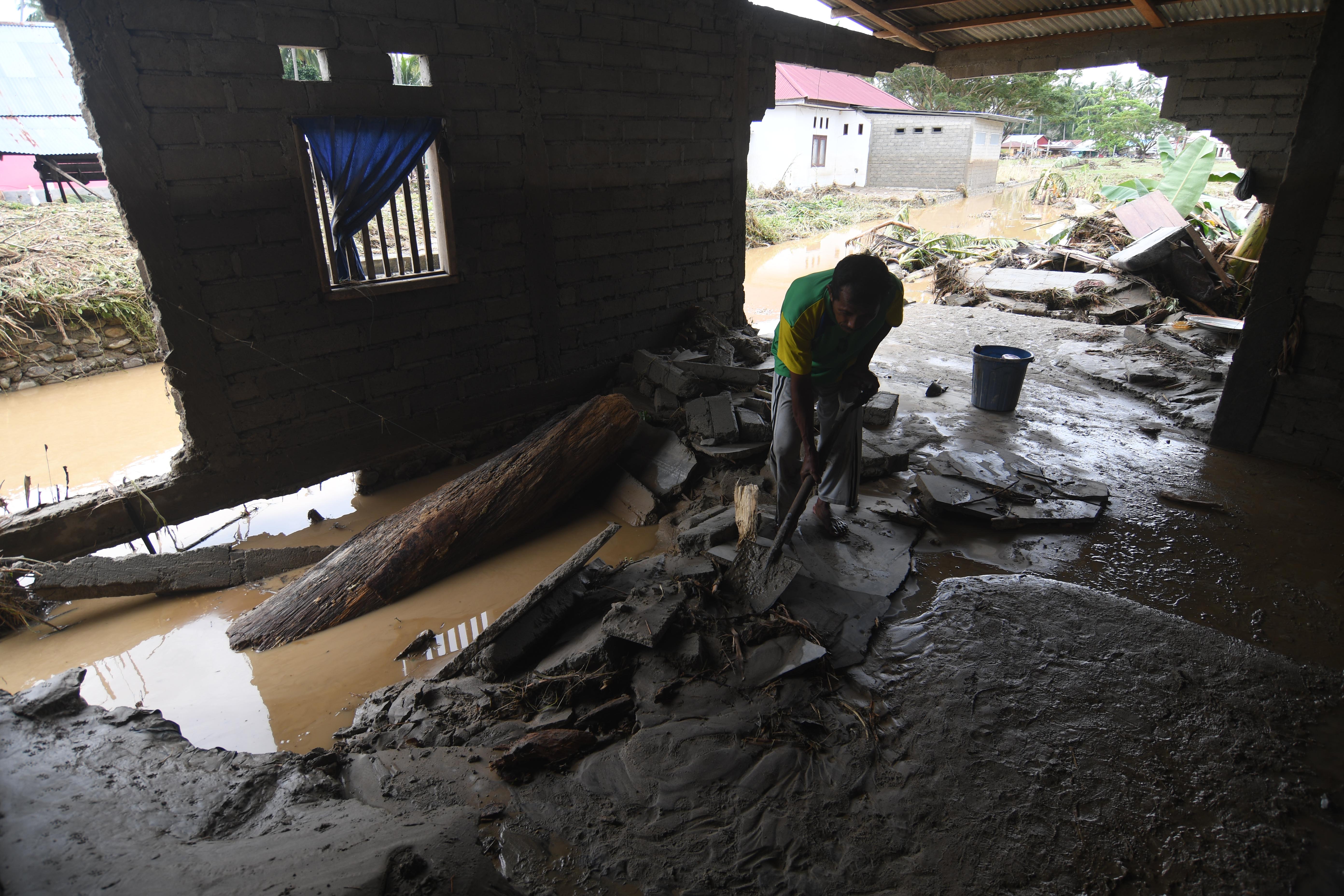 Ilustrasi warga membersihkan material dari dalam rumahnya yang rusak akibat diterjang banjir