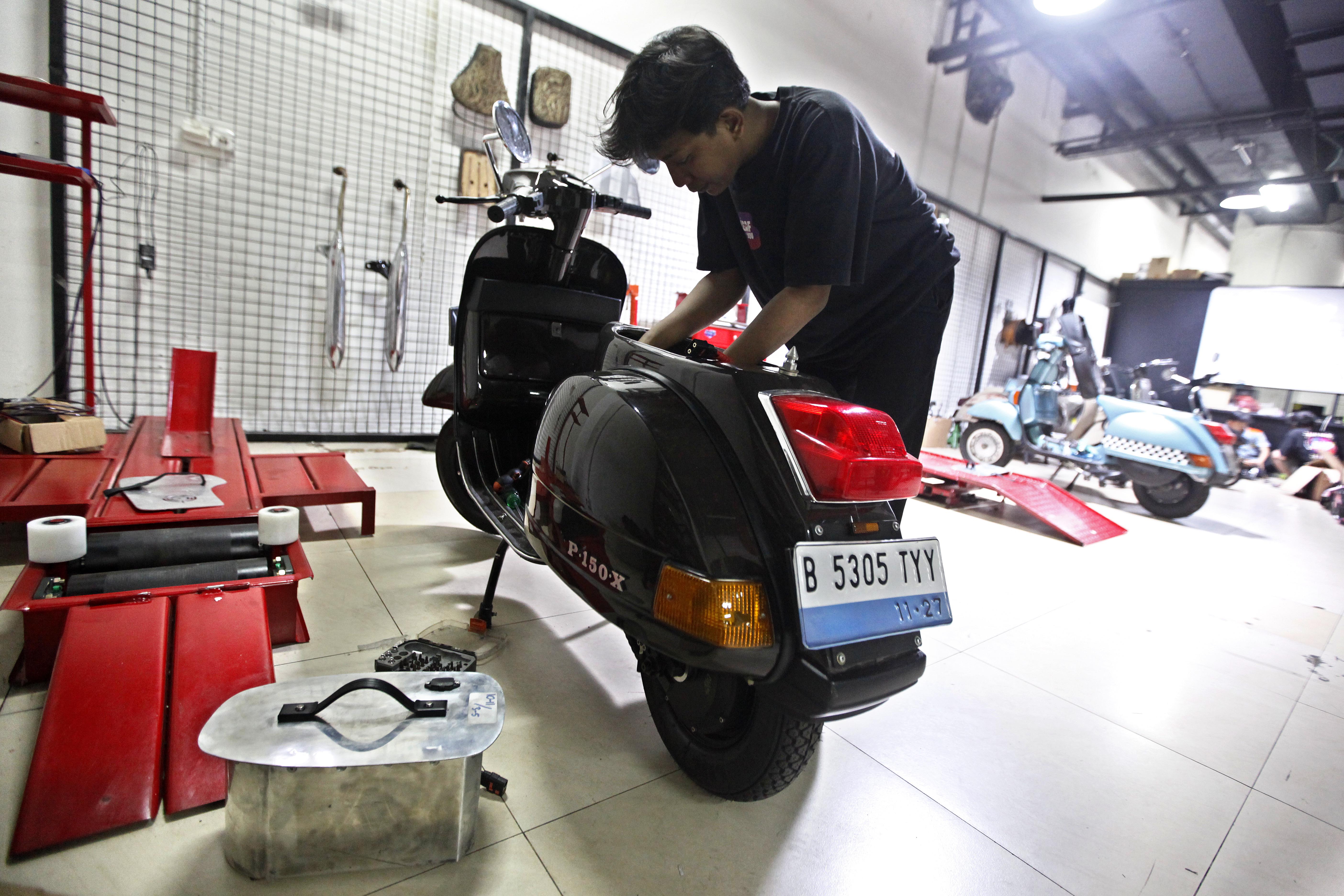 Pekerja merakit kendaraan bermotor konvensional yang dikonversi menjadi motor listrik di bengkel modifikasi di Gedung Smesco, Jakarta. 
