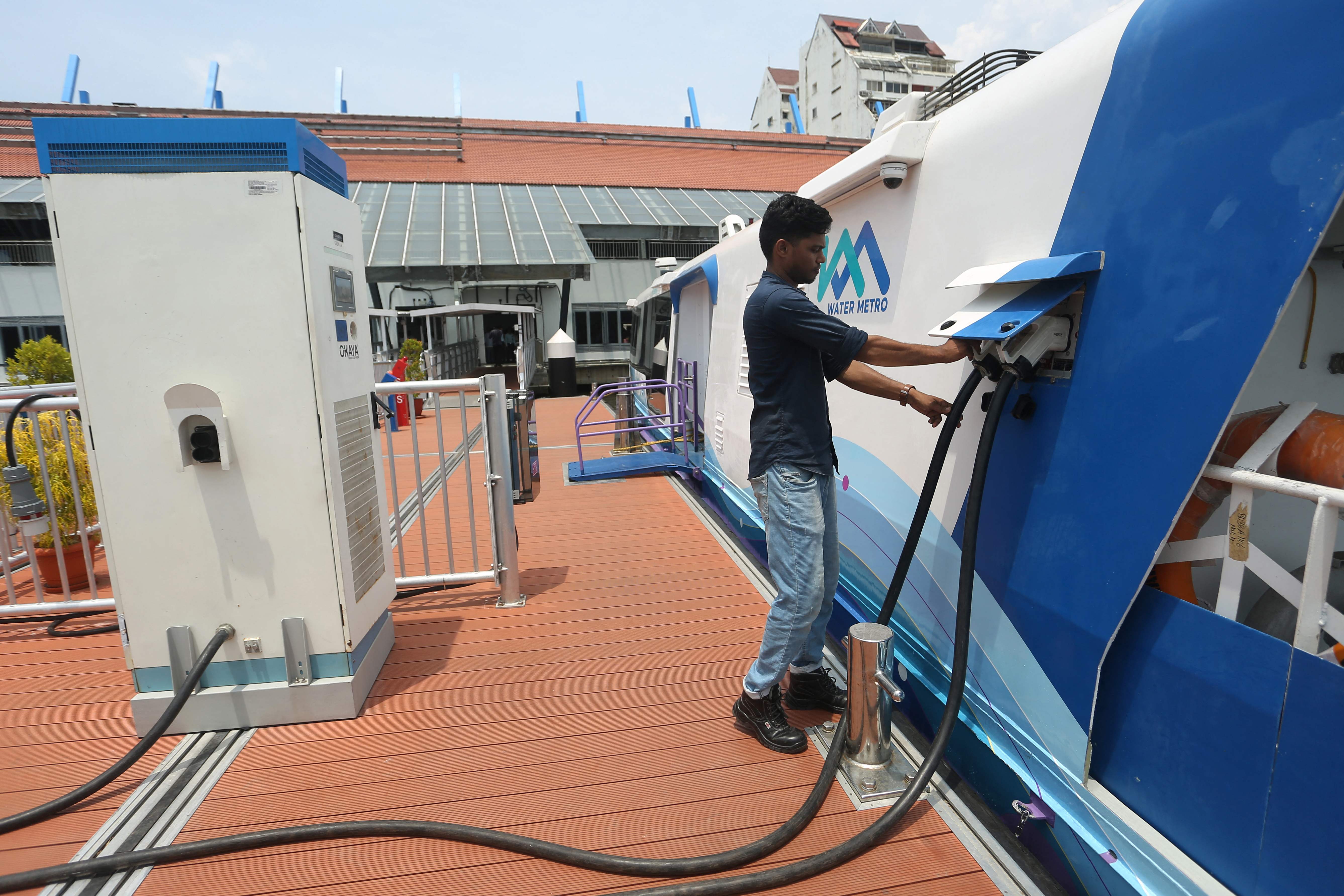 Seorang pekerja melakukan isi ulang baterai kapal penumpang Kochi Water Metro berbasis listrik.