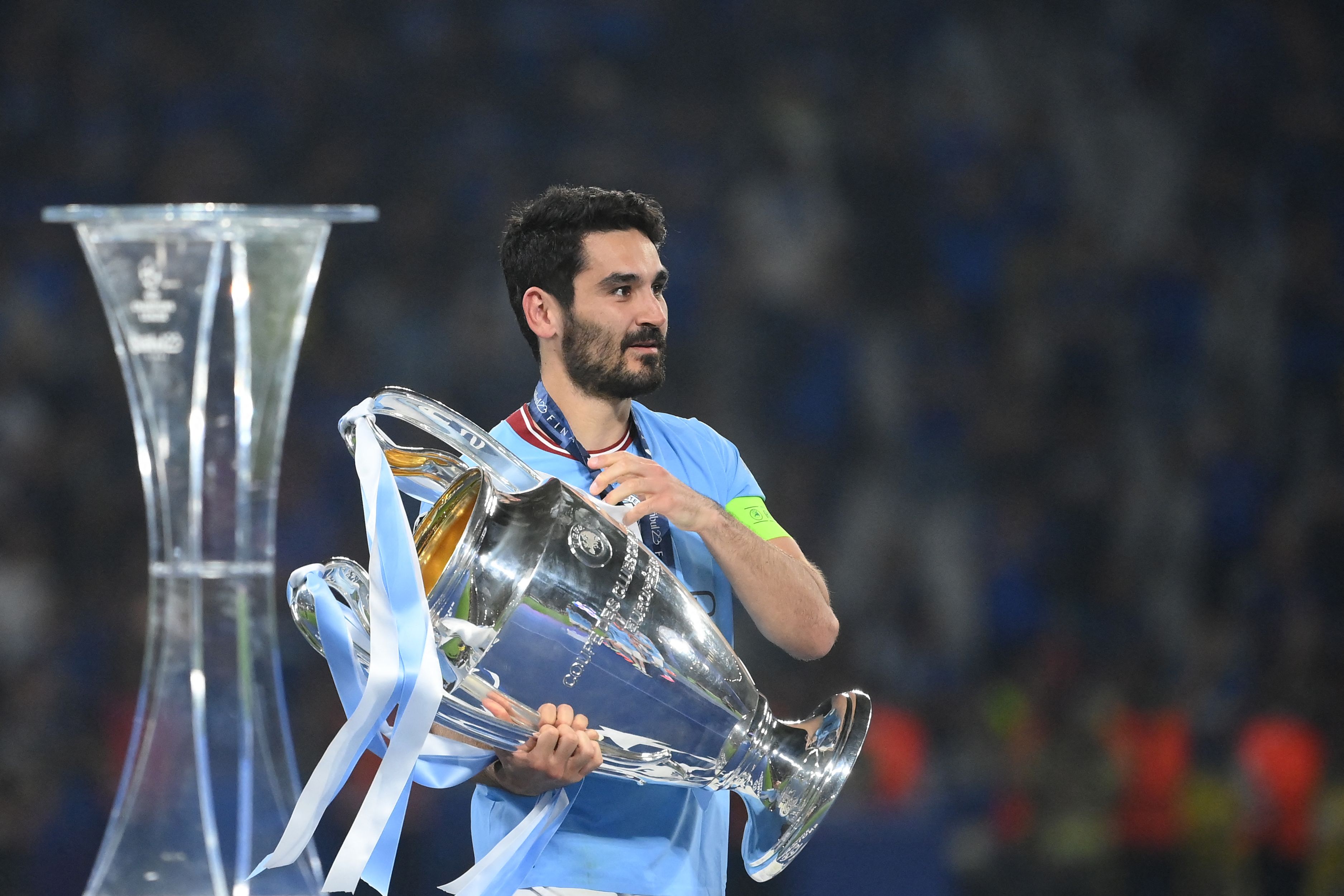 Gelandang Manchester City Ilkay Gundogan membawa trofi Liga Champions.