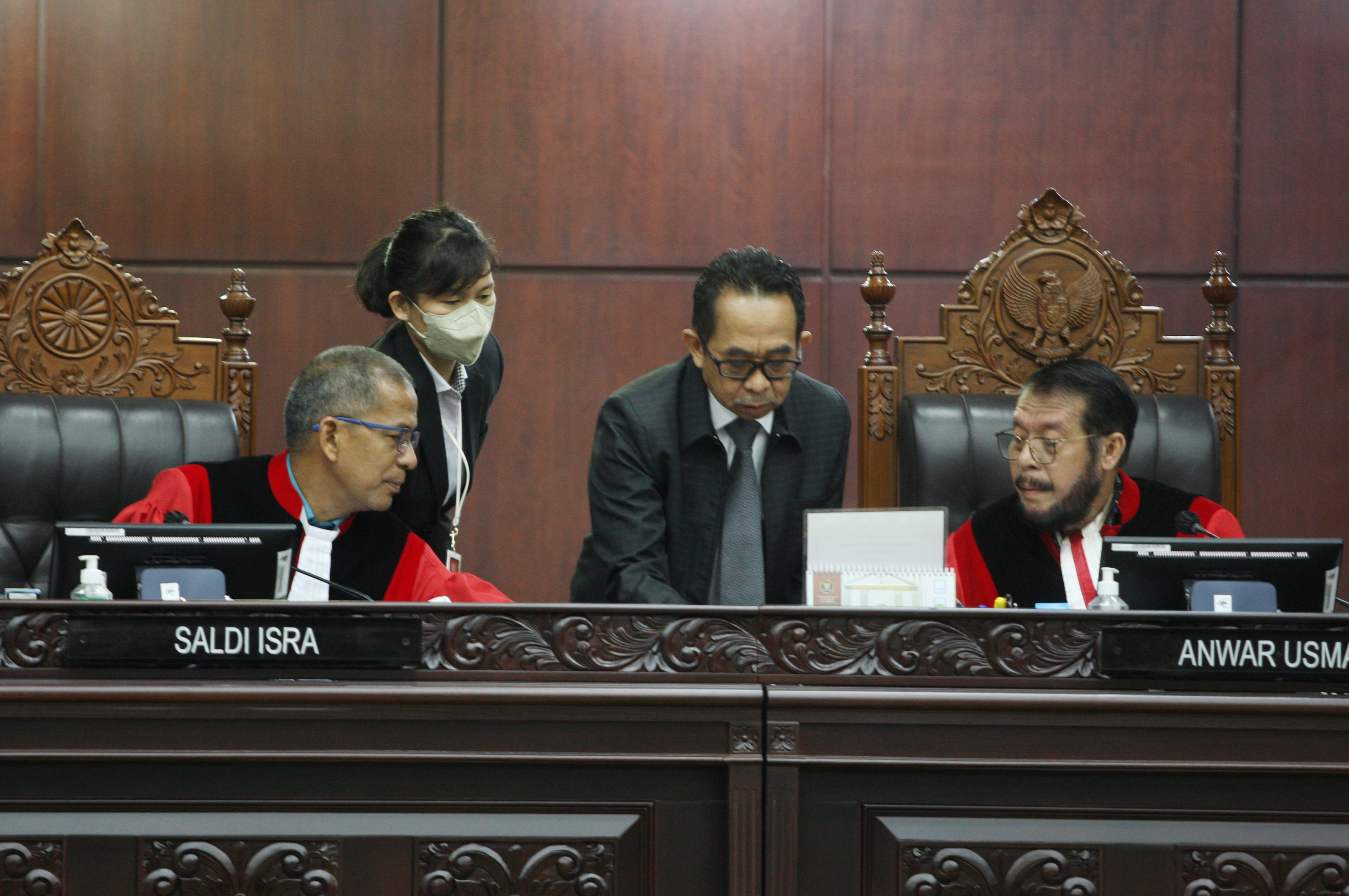 Ketua Hakim Konstitusi Anwar Usman (kanan) dan Hakim Konstitusi Sadil Isra (kiri) berdiskusi dengan petugas di sela pengucapan amar putusan 