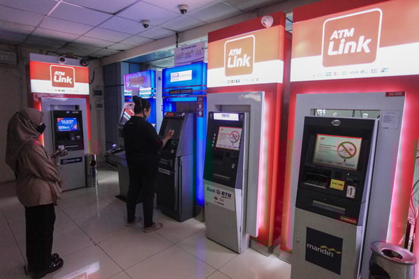 Warga bertansaksi melalui mesin anjungan tunai mandiri (ATM).