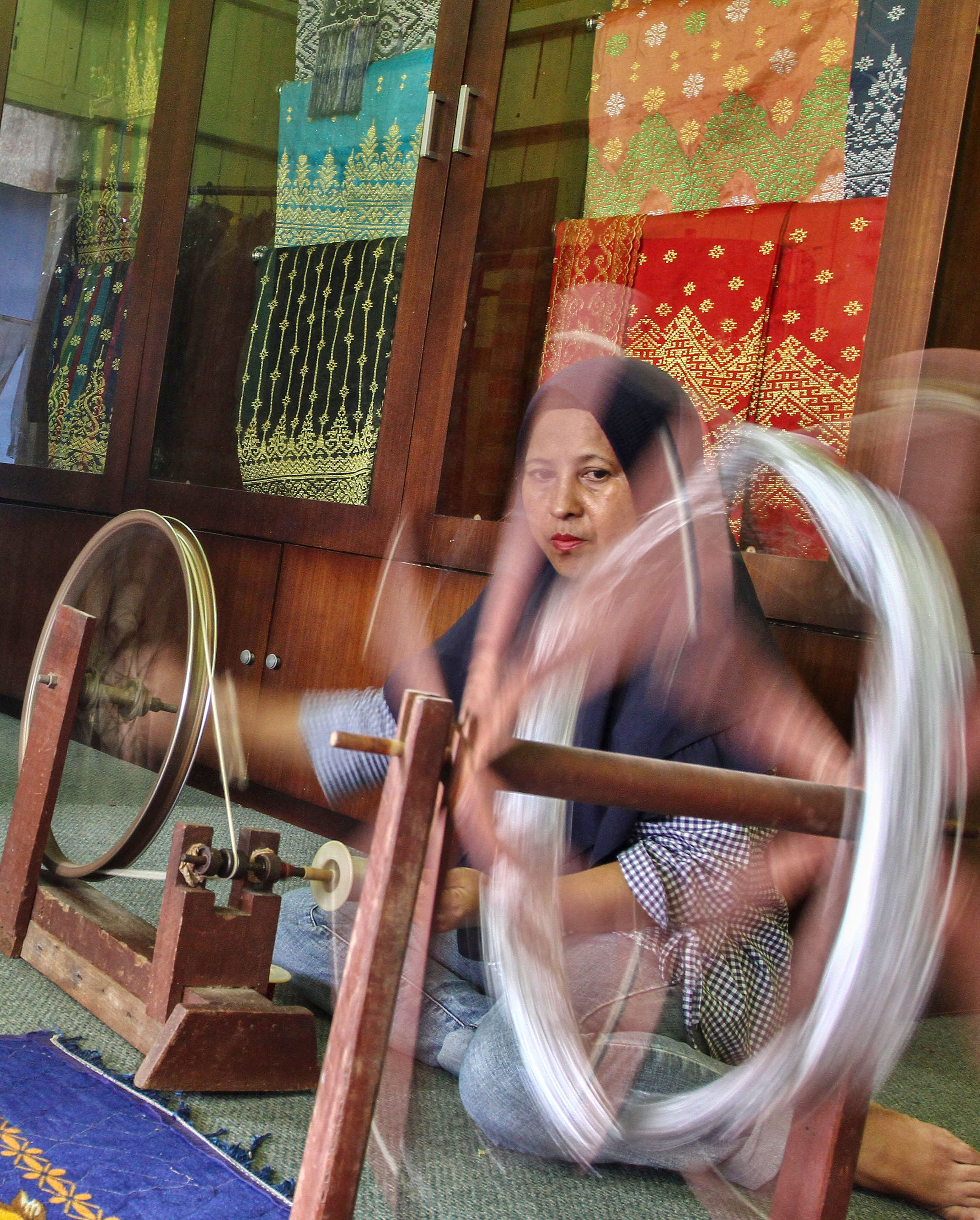 Ilustrasi:  Perajin menggulung (mengelos) benang tenun untuk pembuatan kain tenun khas Melayu Riau di Rumah Kerajinan Tenun, Pekanbaru, Riau