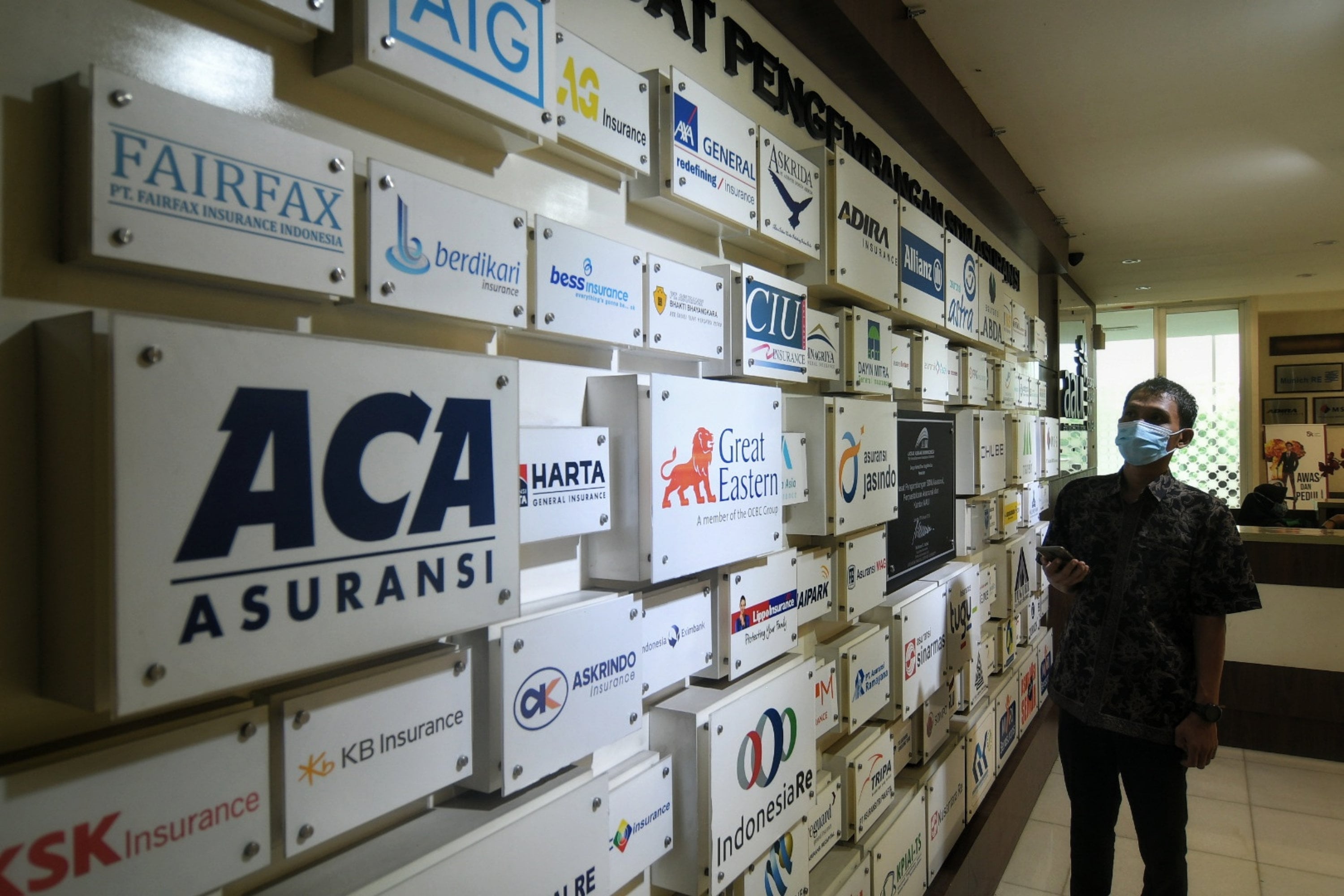 Karyawan sedang melihat logo-logo perusahaan asuransi di Kantor Asosiasi Asuransi Umum Indonesia (AAUI), Jakarta, Selasa (11/02/2020).