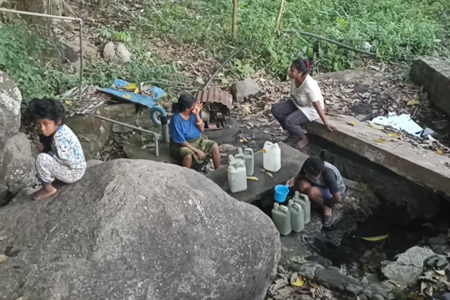 Warga mengambil air bersih dari mata air.