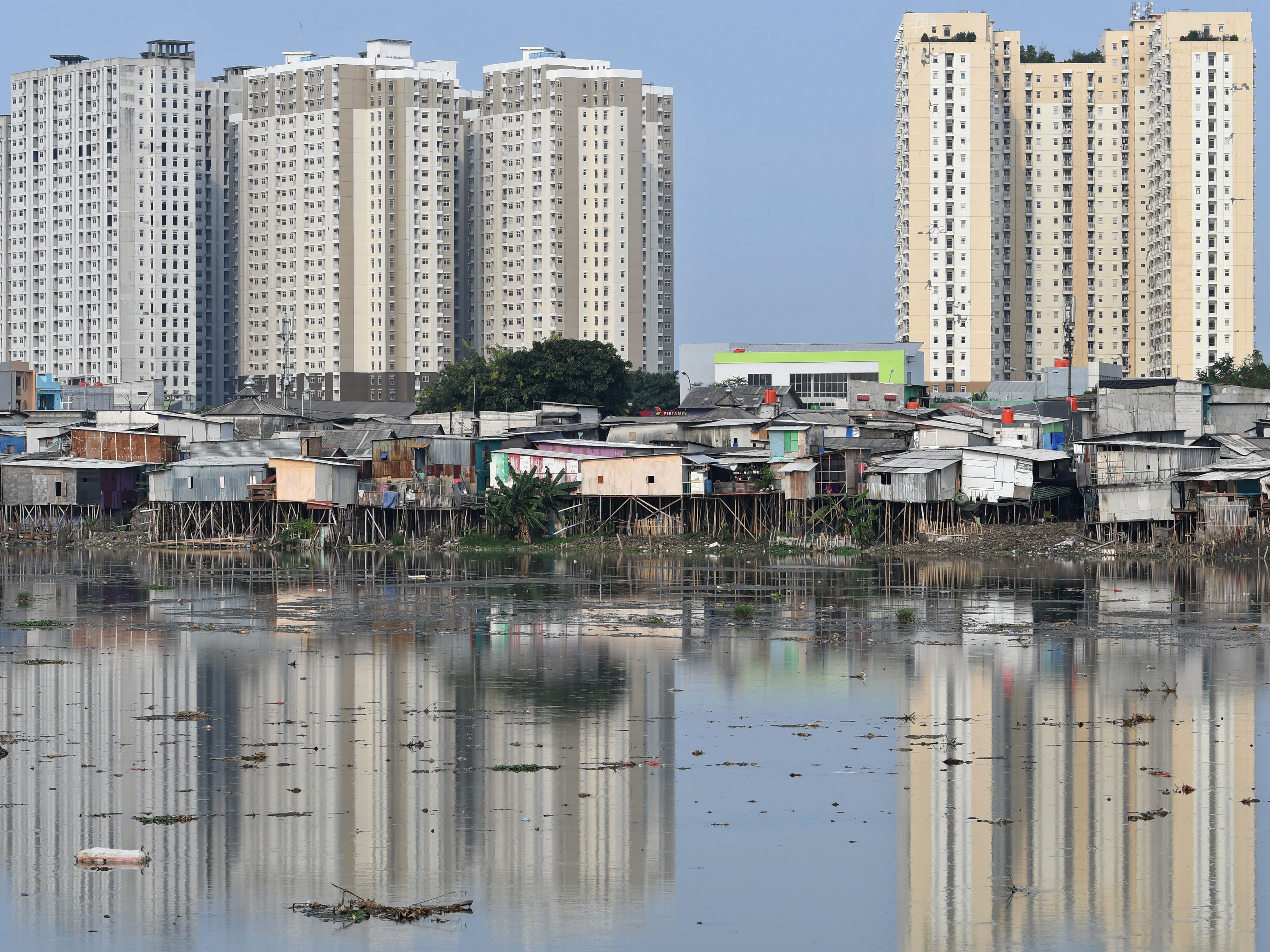 Rumah-rumah semipermanen berdiri di atas tepi Waduk Pluit, Jakarta.