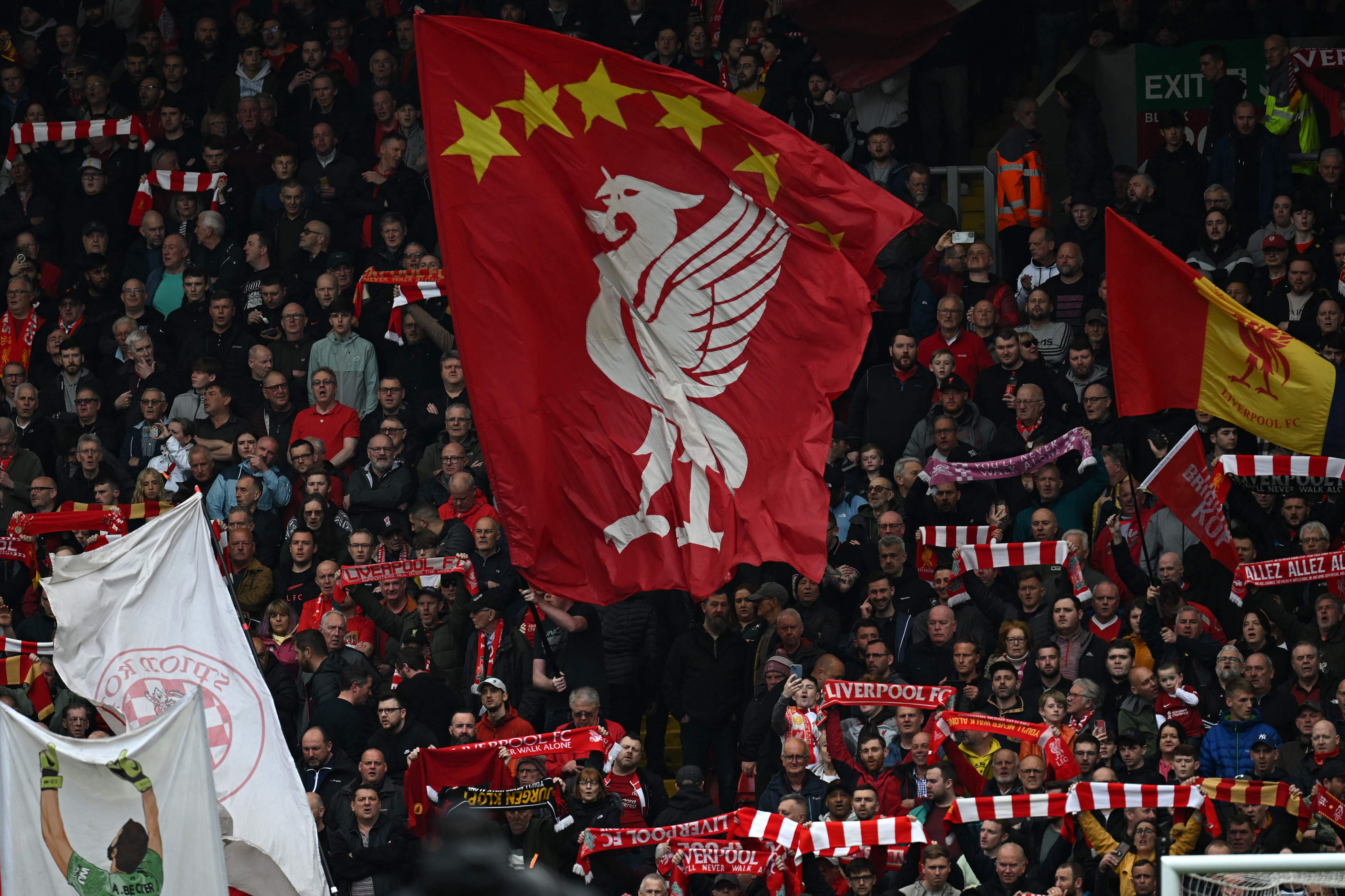 Suporter mengibarkan bendera logo Liverpool.