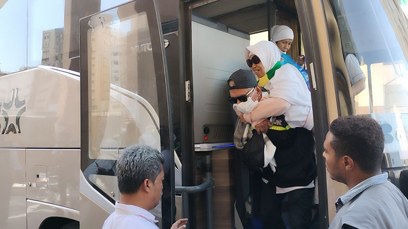  Petugas menggendong jemaah berkursi roda turun dari bus setiba di Hotel Al Madinah Ergwan, Madinah, Senin (10/7/2023).  