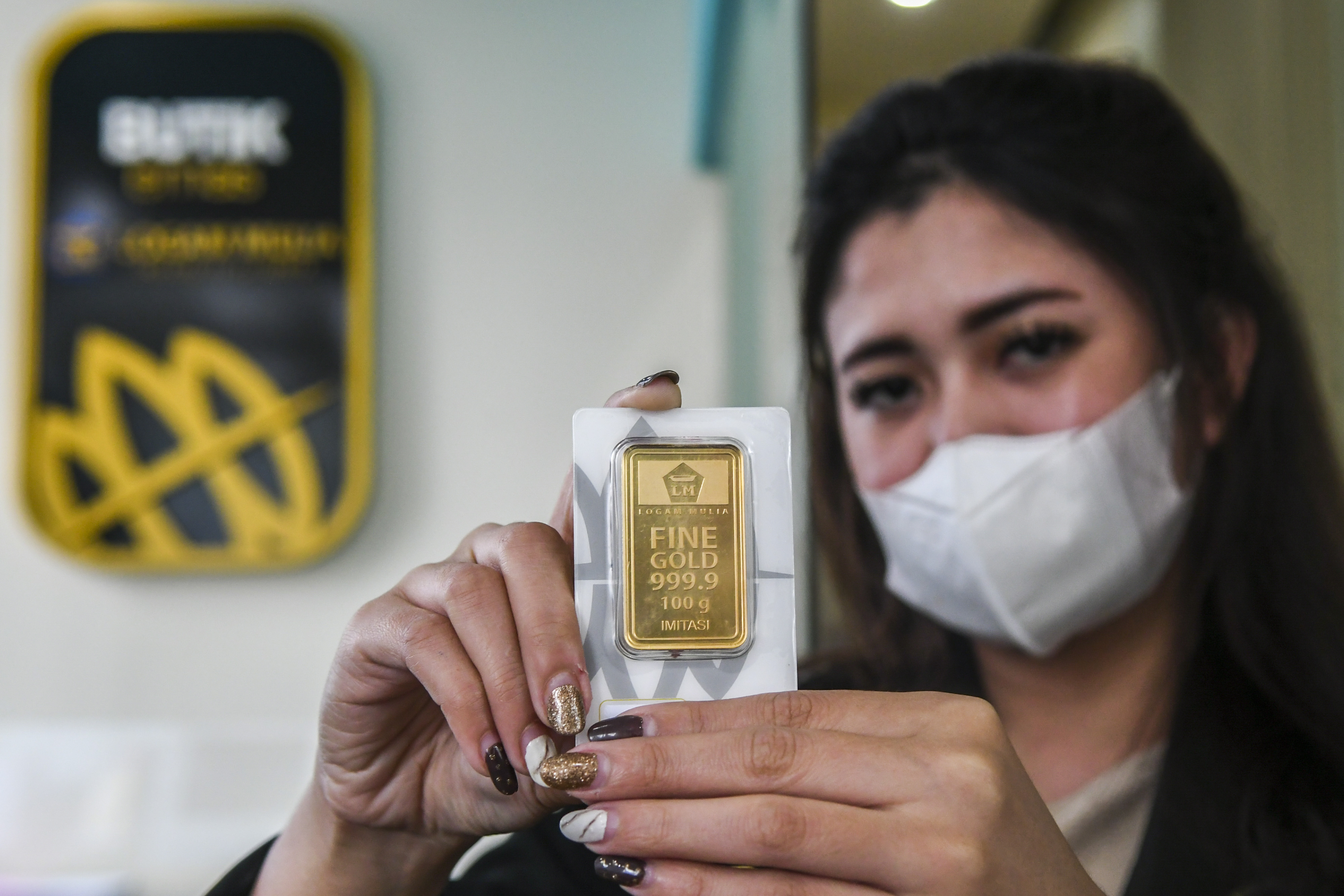 Karyawan menunjukan emas batangan di Butik Emas Antam, Kebon Sirih, Jakarta, Senin (18/1/2021).