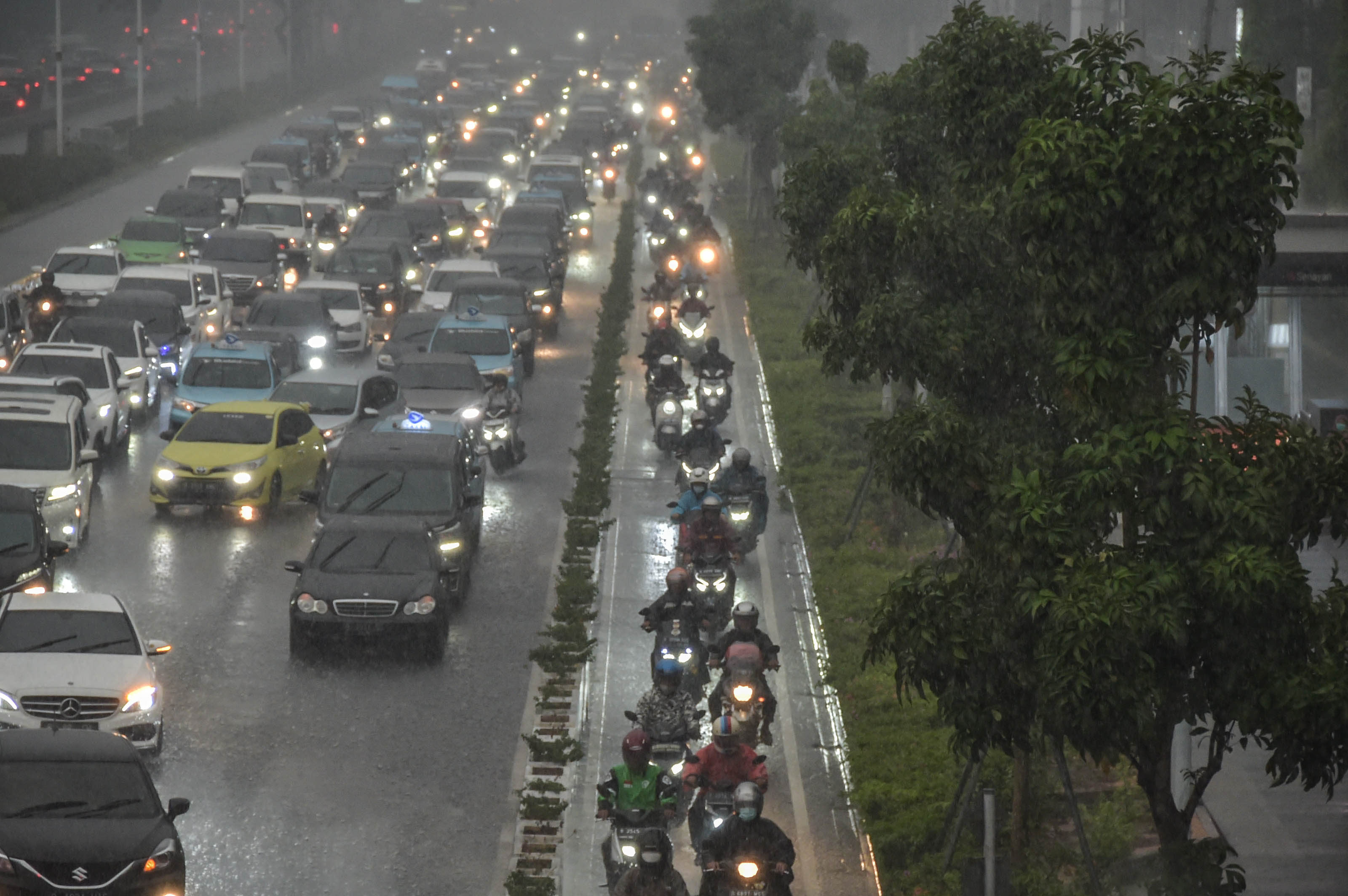 Ilustrasi pengemudi berkendara menerobos hujan di Jalan Sudrman, Jakarta