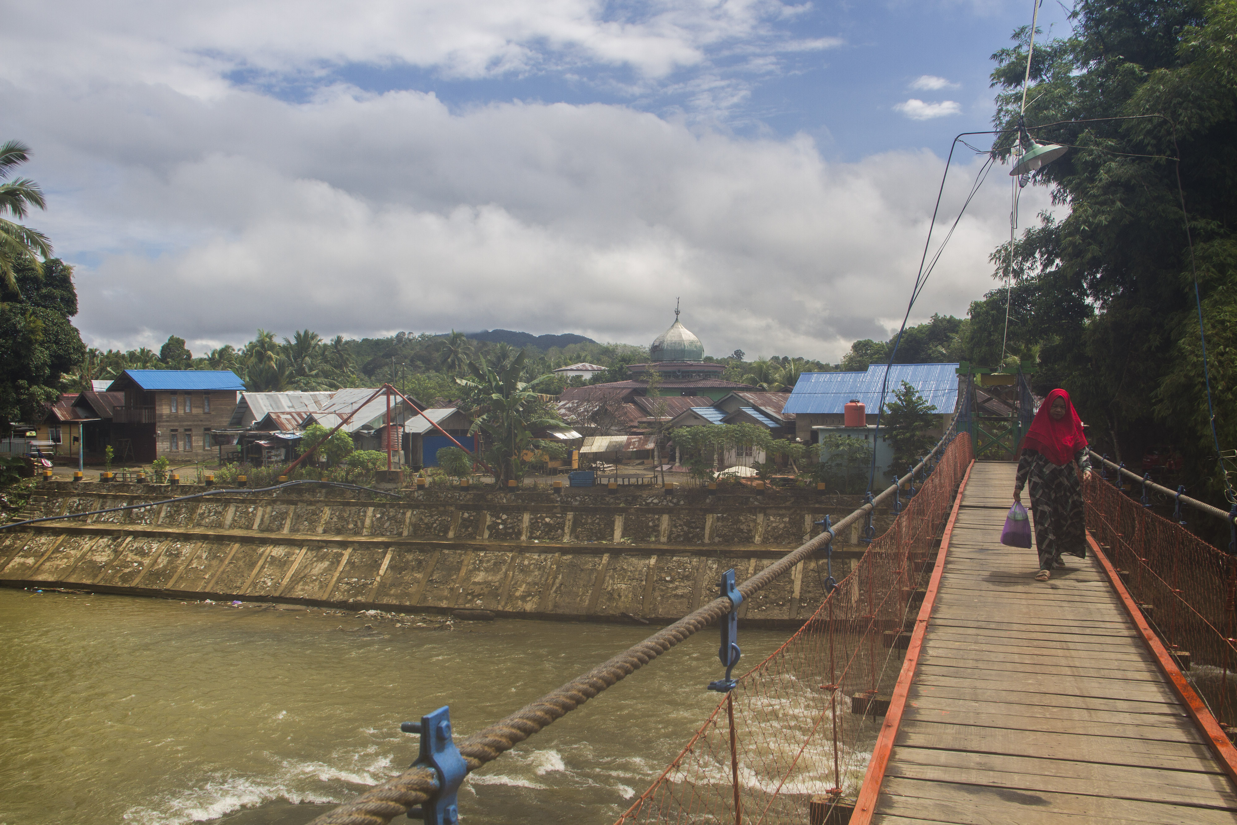 Seorang warga berjalan melintasi jembatan gantung di Desa Waki, Kabupaten Hulu Sungai Tengah,, Kalimantan Selatan.