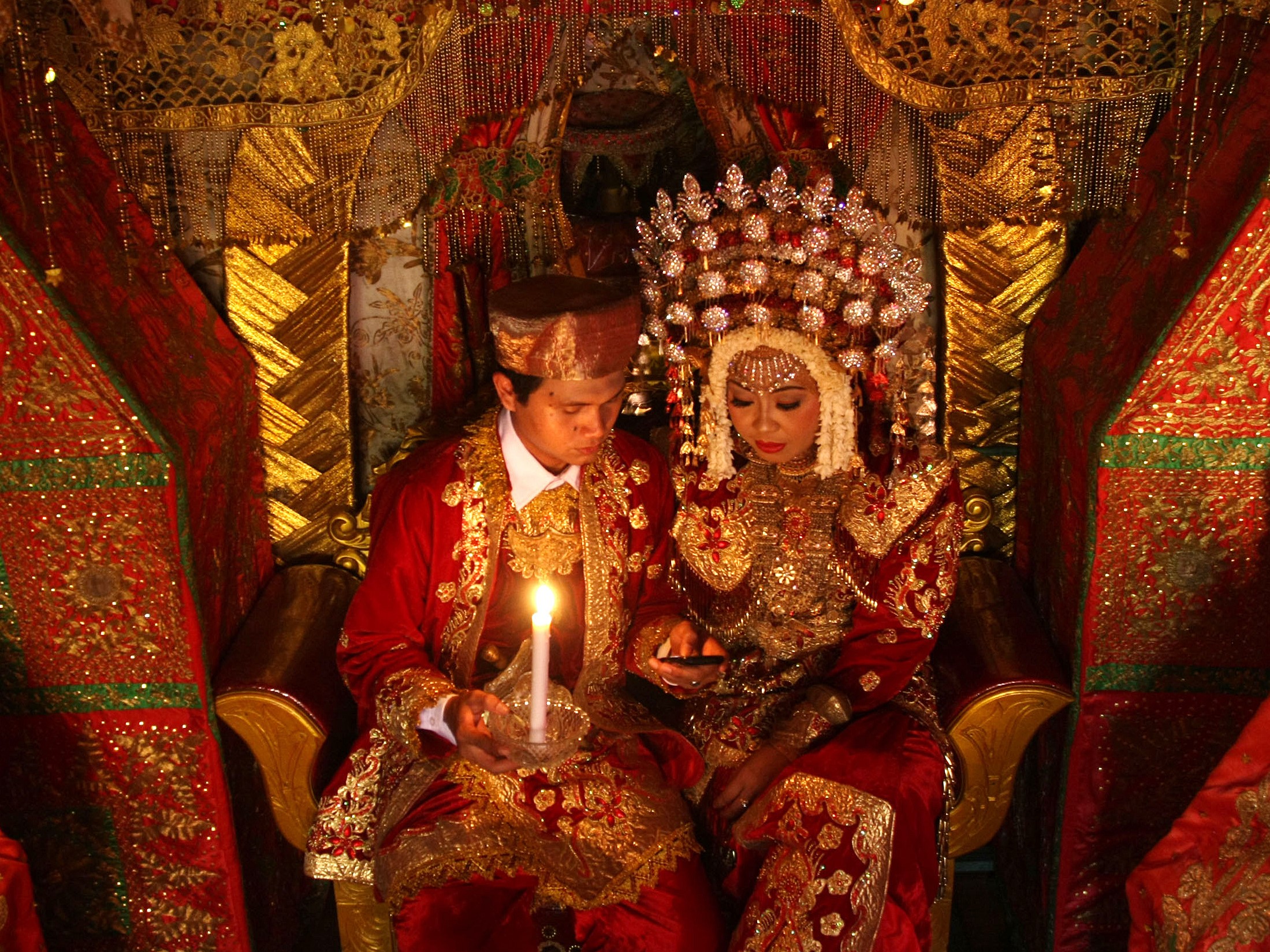 Marapulai dan Anak Daro (Pengantin) memegang lilin saat resepsi perkawinan akibat pemadaman listrik bergilir di Kota Padang, Sumbar.