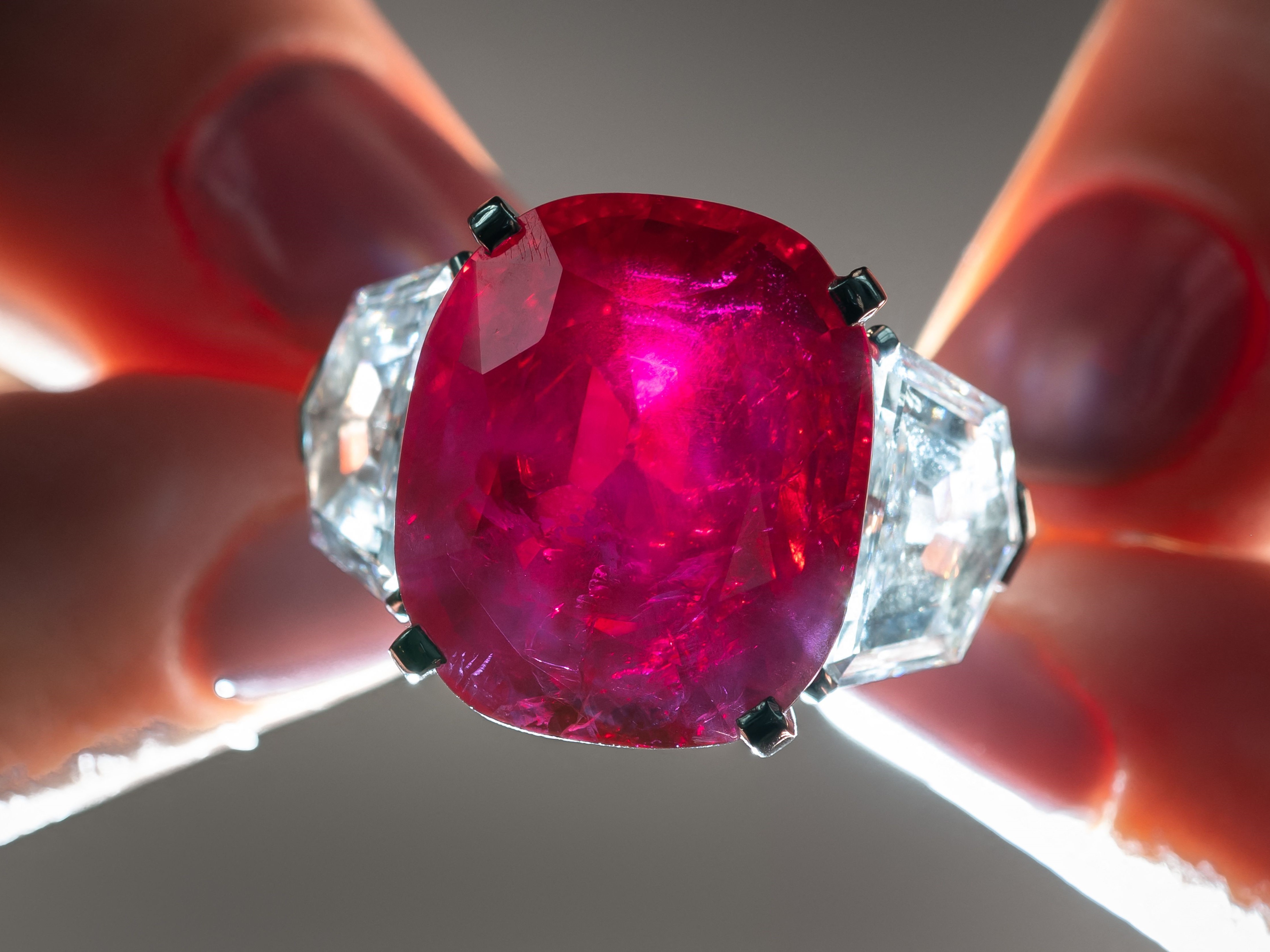 Pegawai rumah lelang Christie memegang Sunrise Ruby, cincin ruby ​​​​dan dan berlian Cartier langka, yang beratnya 25,59 karat.