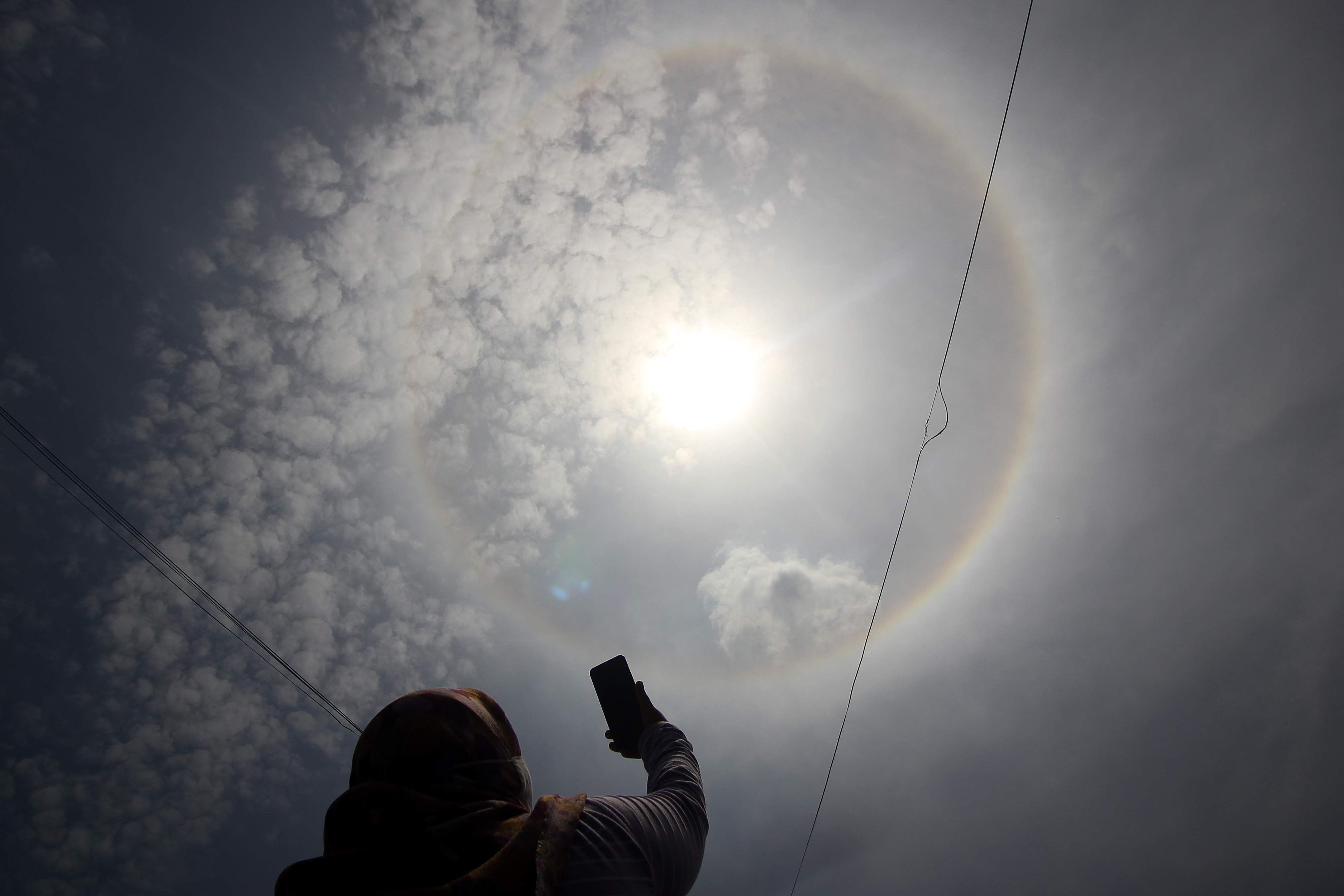Warga menyaksikan fenomena halo matahari di Surabaya, Jawa Timur, Minggu (15/11/2020).