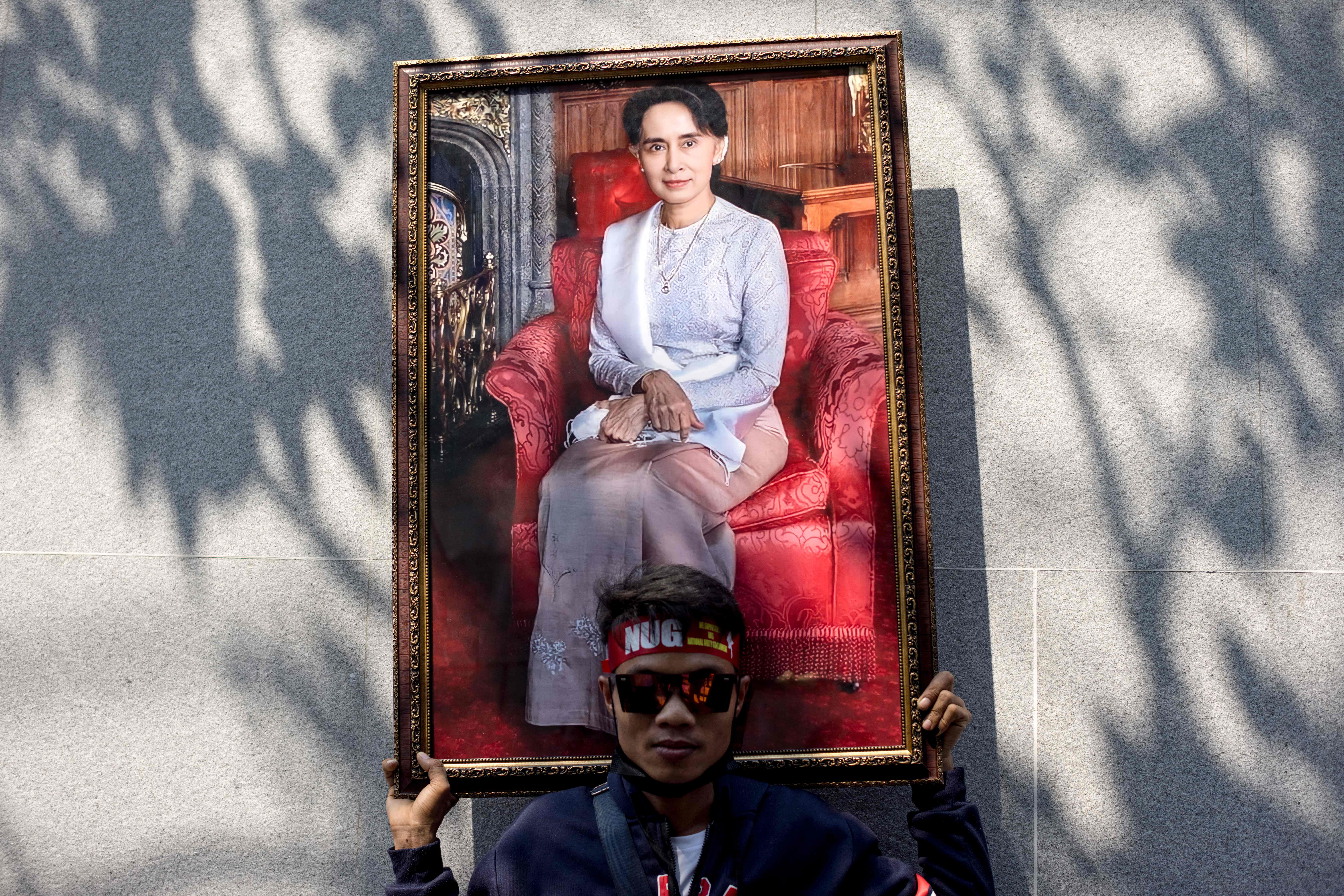 Seorang demonstran membawa gambar Aung San Suu Kyi saat melakukan aksi di depan Kedubes Myanmar di Bangkok, Thailand.