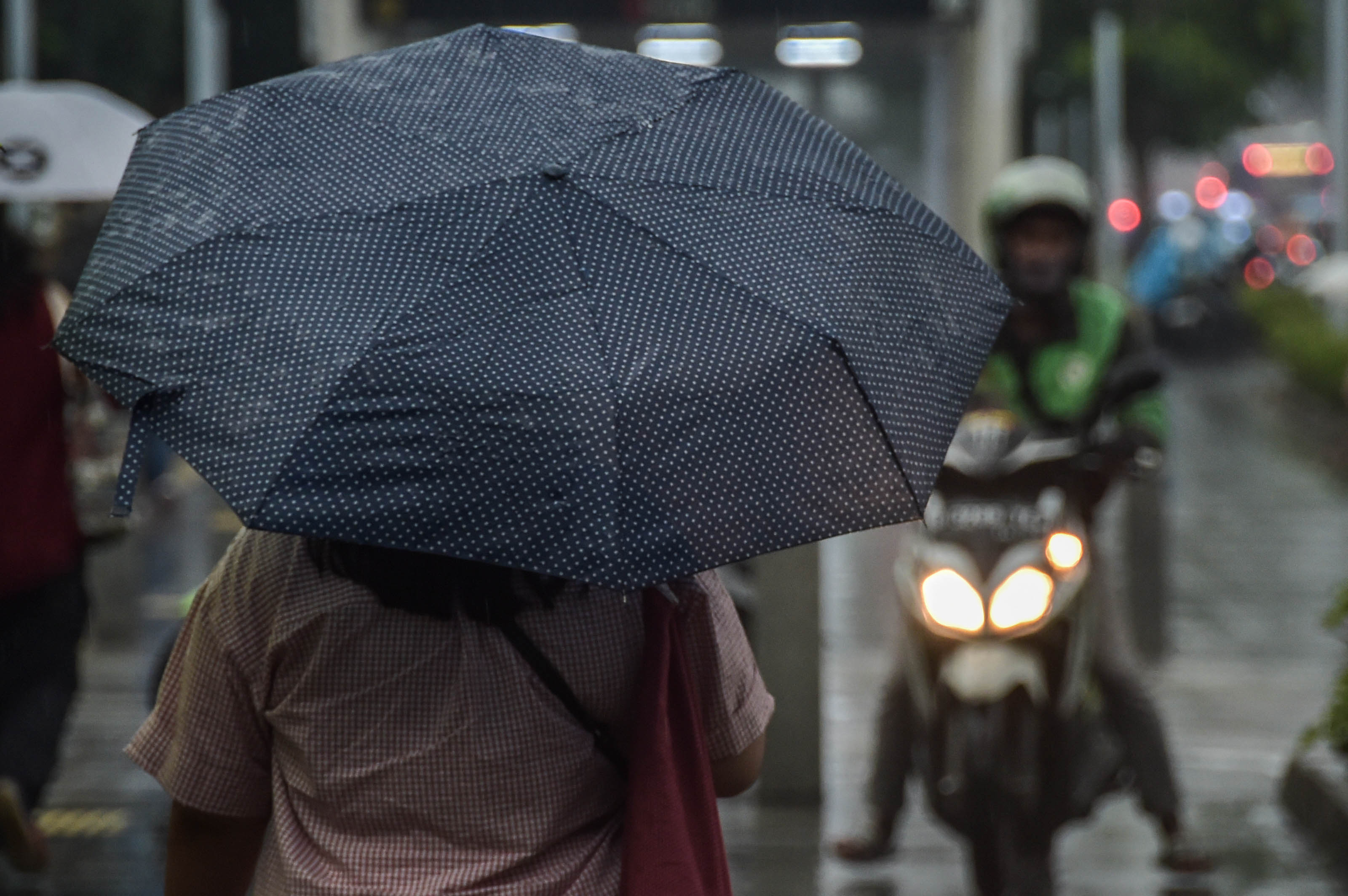 Sejumlah warga berjalan melewati hujan di Senayan, Jakarta (5/5).