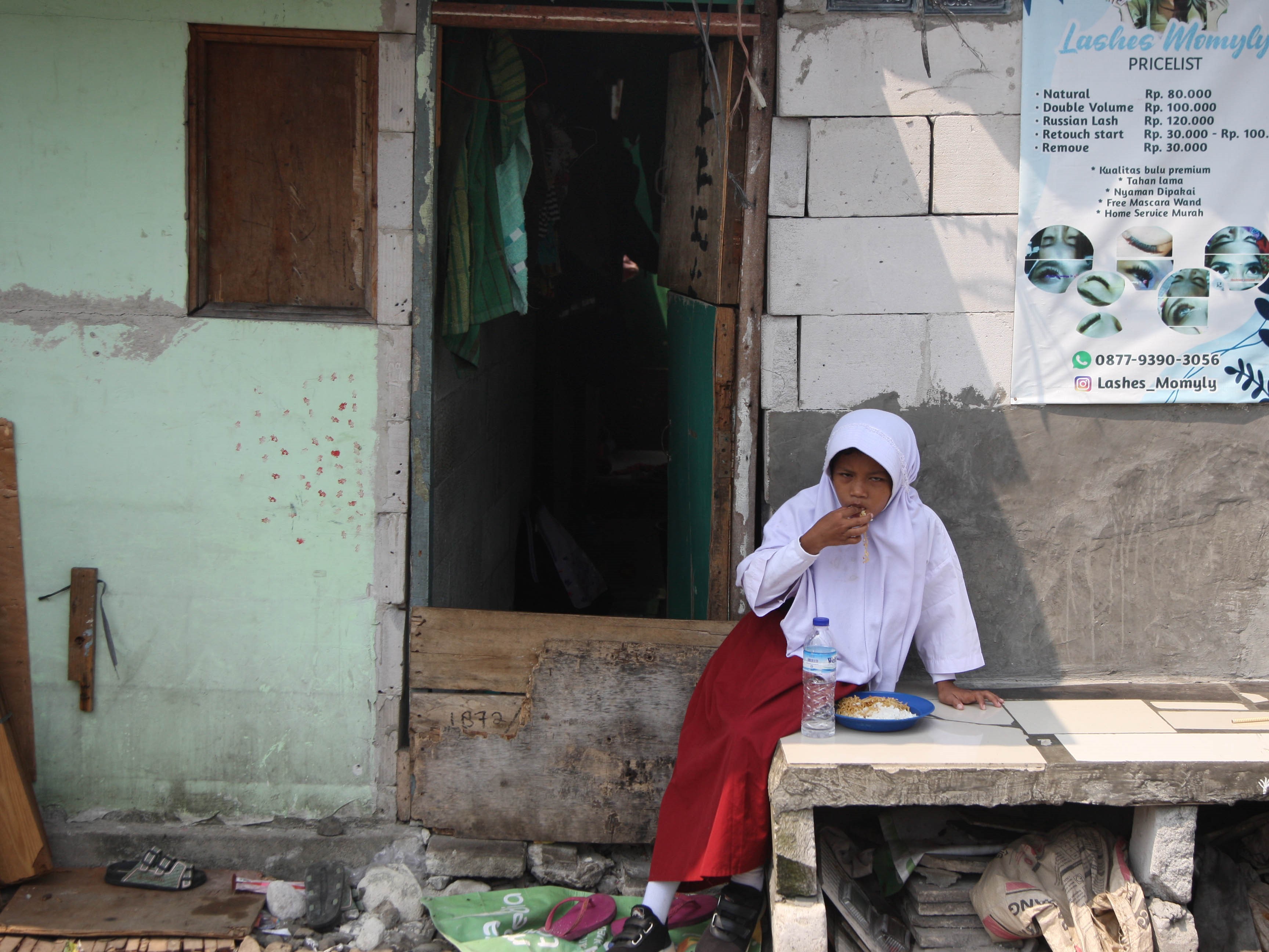 Siswi sarapan sebelum berangkat sekolah dari rumahnya di pemukiman kumuh dan padat penduduk Kampung Bandan, Pademangan, Jakarta Utara.