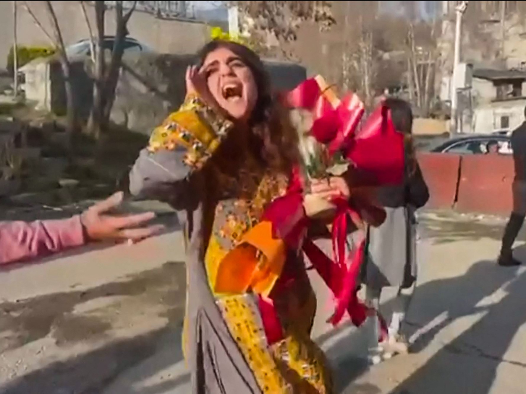 Aktivis dan jurnalis Iran Sepideh Gholian berjalan dengan karangan bunga di luar tembok penjara Evin di Teheran, setelah pembebasannya.