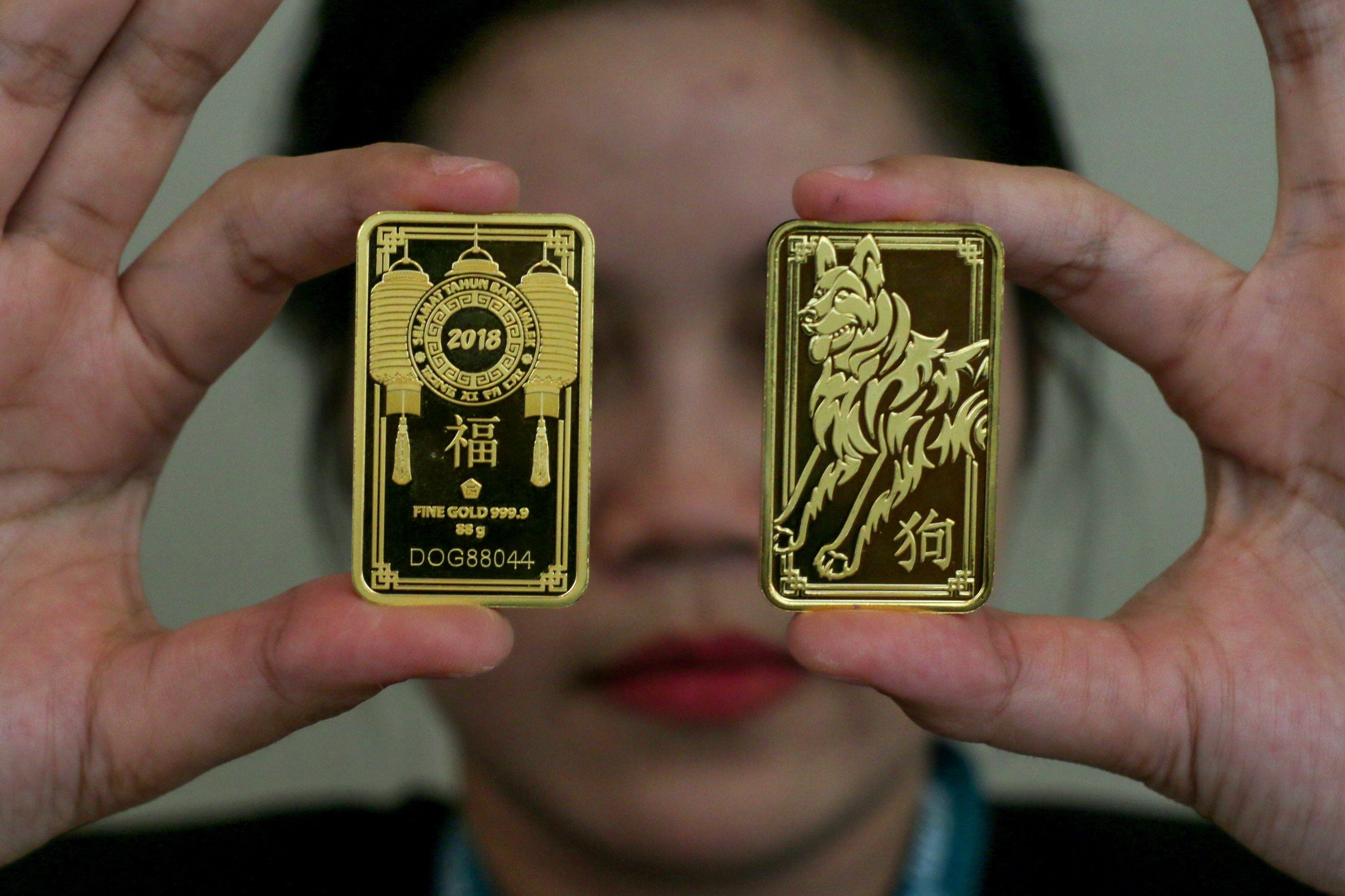 Customer service butik Logam Mulia (LM) menunjukkan emas batangan bergambar seekor anjing saat diluncurkan di Jakarta, Kamis (18/1/2018).