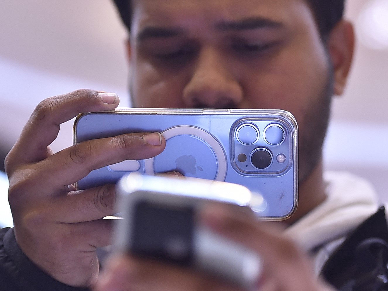 Seorang pria mengambil gambar Xiaomi 13 Pro baru dengan perangkat Apple iPhone di Barcelona, Spanyol.