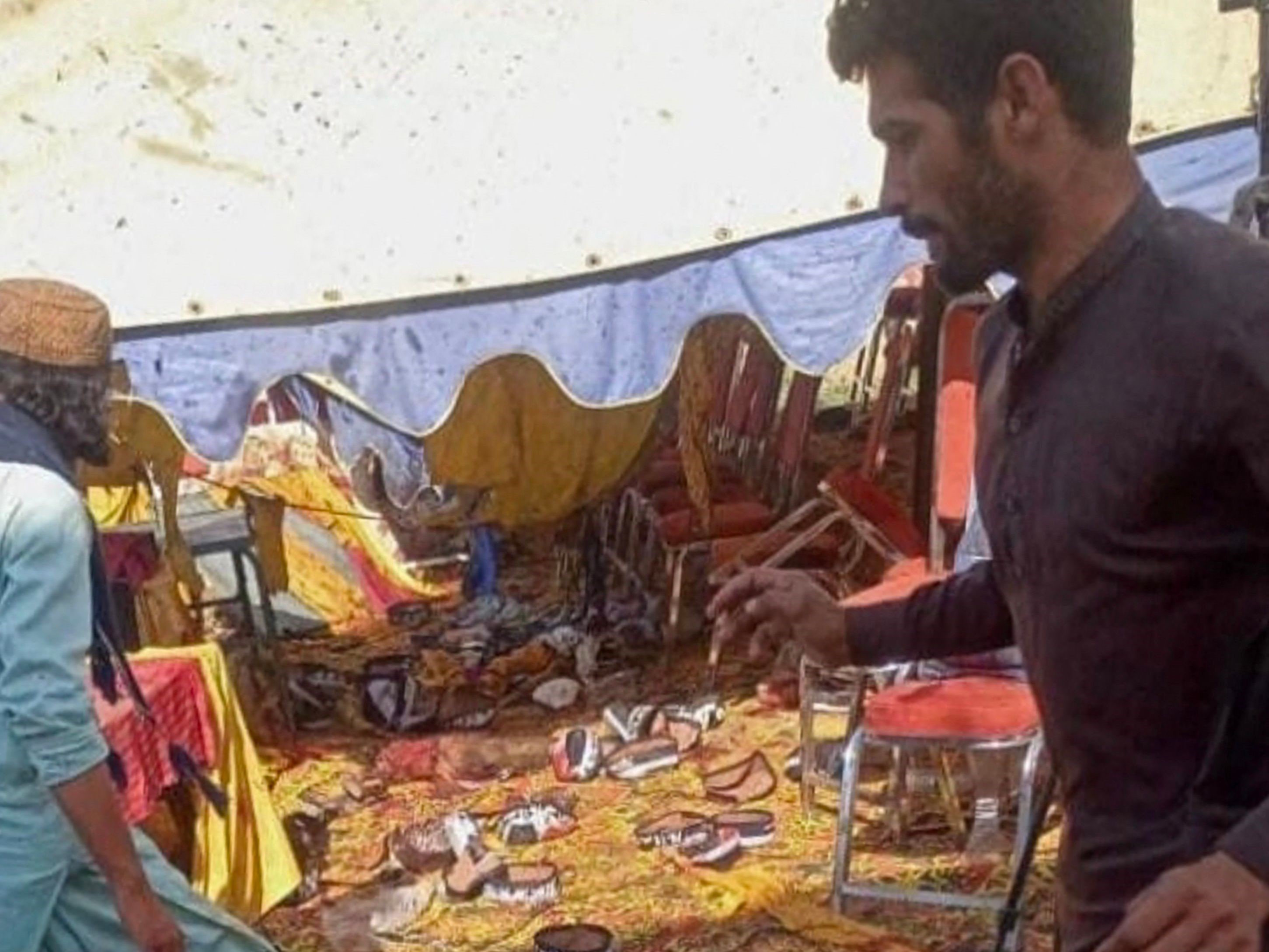 Para pria berkumpul di lokasi ledakan bom di distrik Bajaur pada 30 Juli 2023.