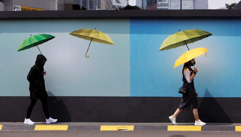  Pejalan kaki berlindung dari sengatan matahari menggunakan payung saat melintasi kawasan Karet. Jakarta, Rabu (25/4/2023)