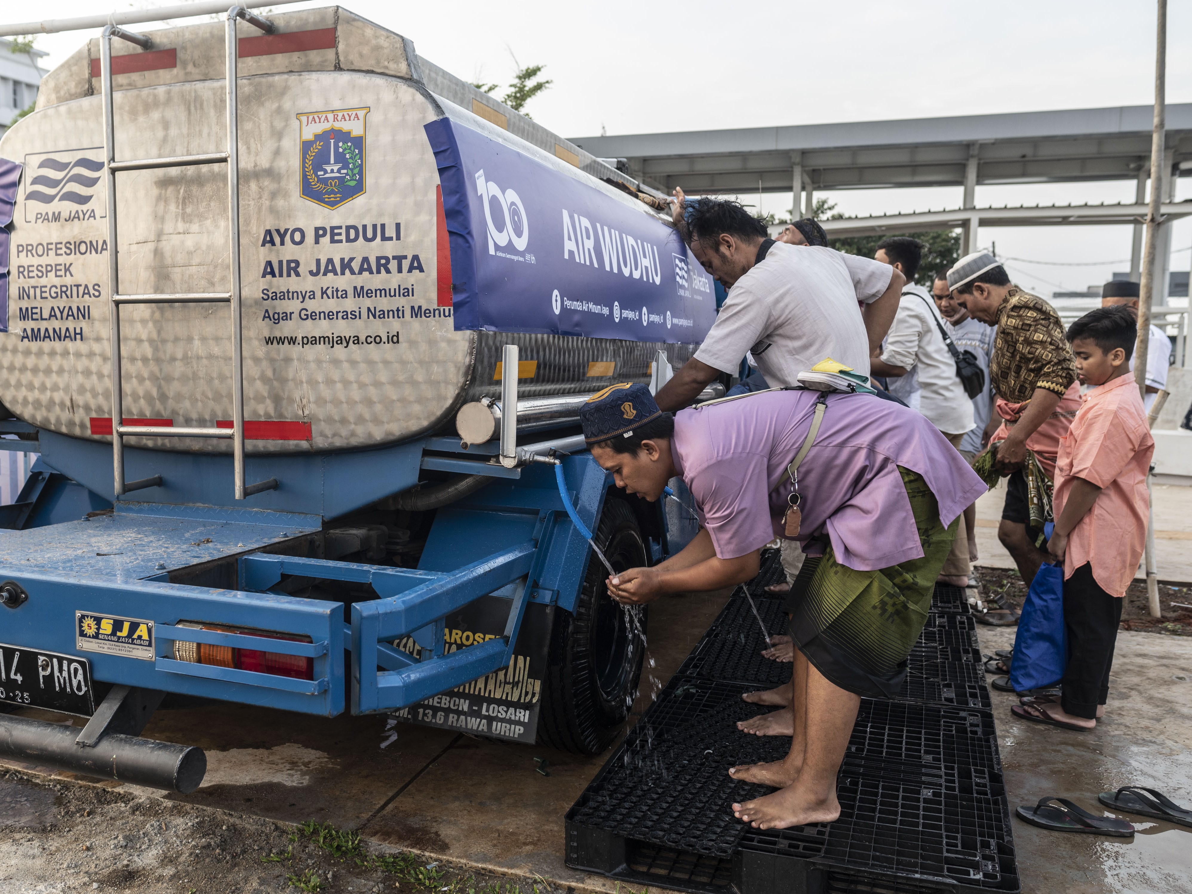 Sejumlah warga berwudhu dari mobil tangki air bersih PAM Jaya sebelum salat Idul Fitri 1443 H di Jakarta International Stadium (JIS).
