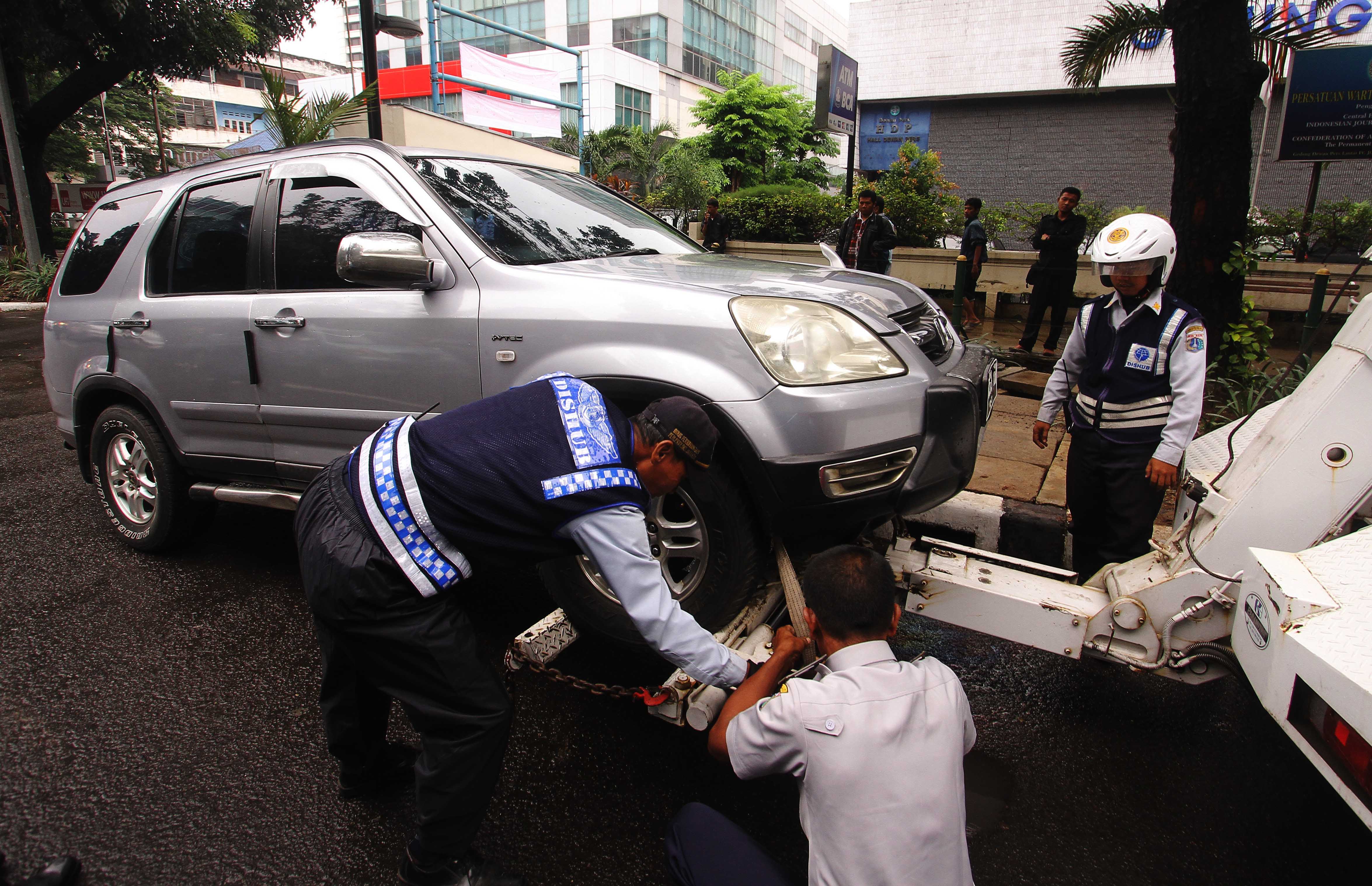  Petugas Dinas Perhubungan menderek kendaraan yang parkir sembarangan di jalan Kebon Sirih, Jakarta, Senin (12/1/2015).