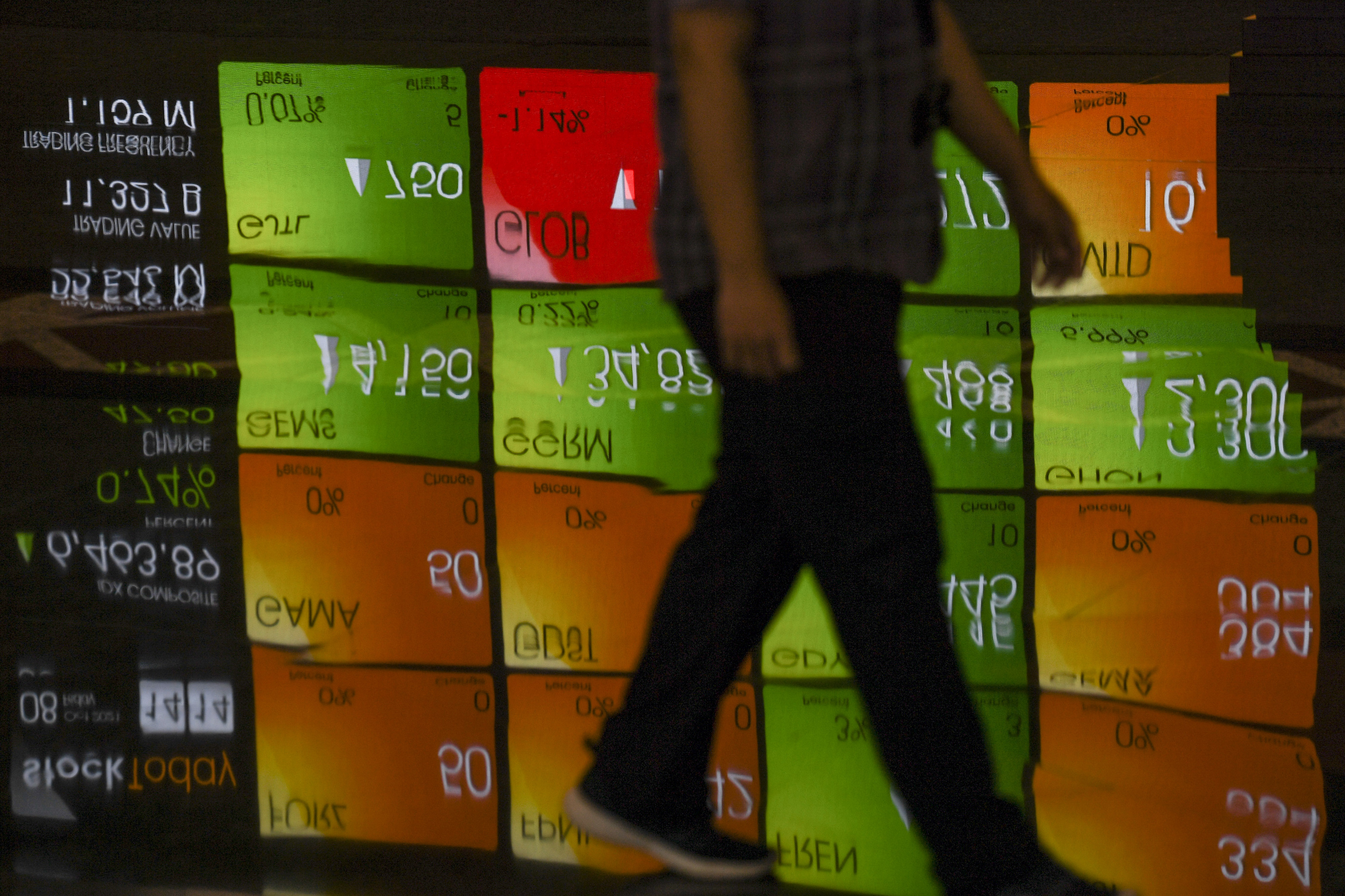  Karyawan melintas di dekat layar yang menampilkan pergerakan saham di Bursa Efek Indonesia, Jakarta, Jumat (8/10/2021).