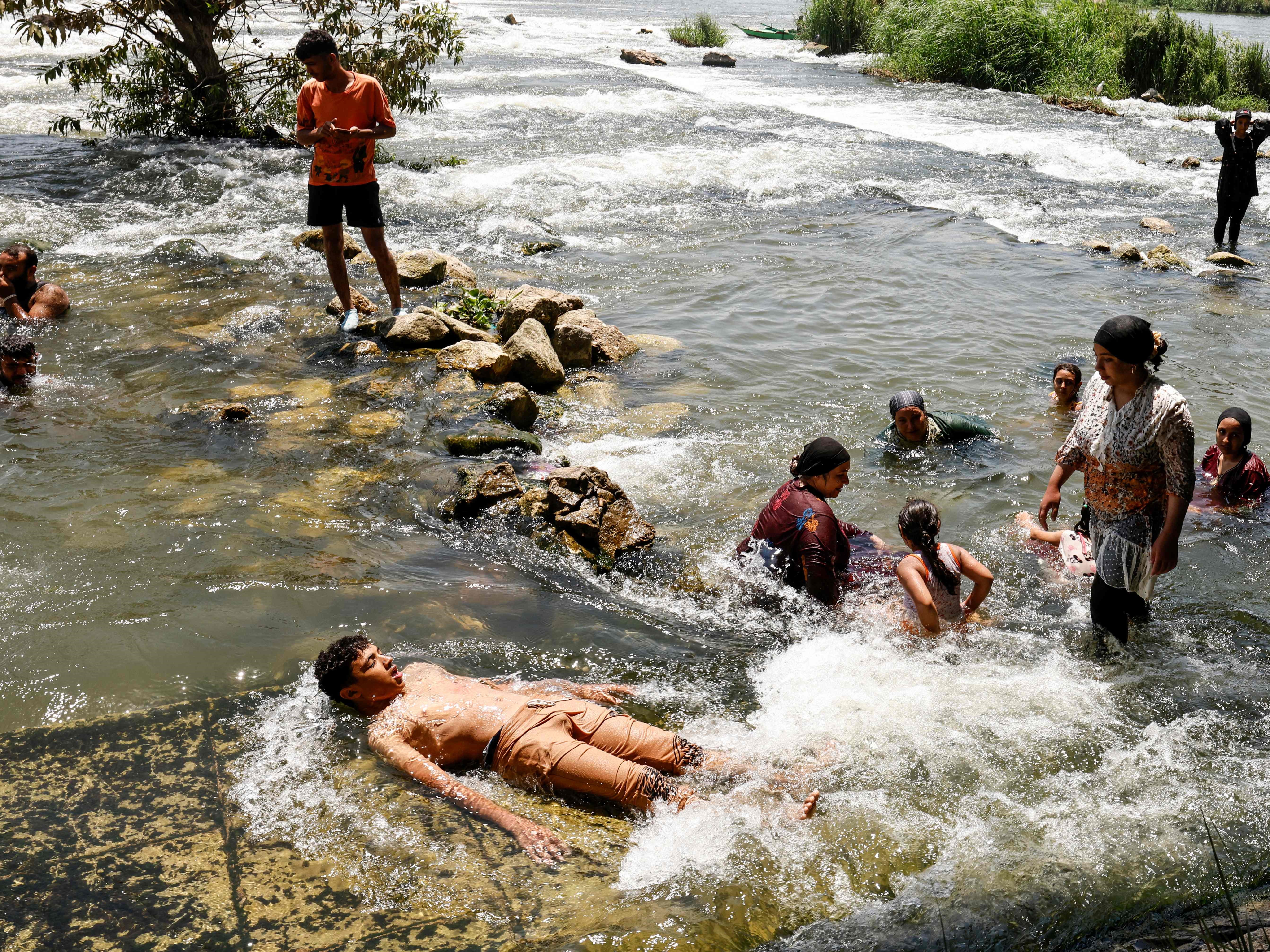 Orang-orang mendinginkan diri di sungai Nil selama gelombang panas di al-Qanater al-Khayreya, di pinggiran Kairo pada 19 Juli 2023.