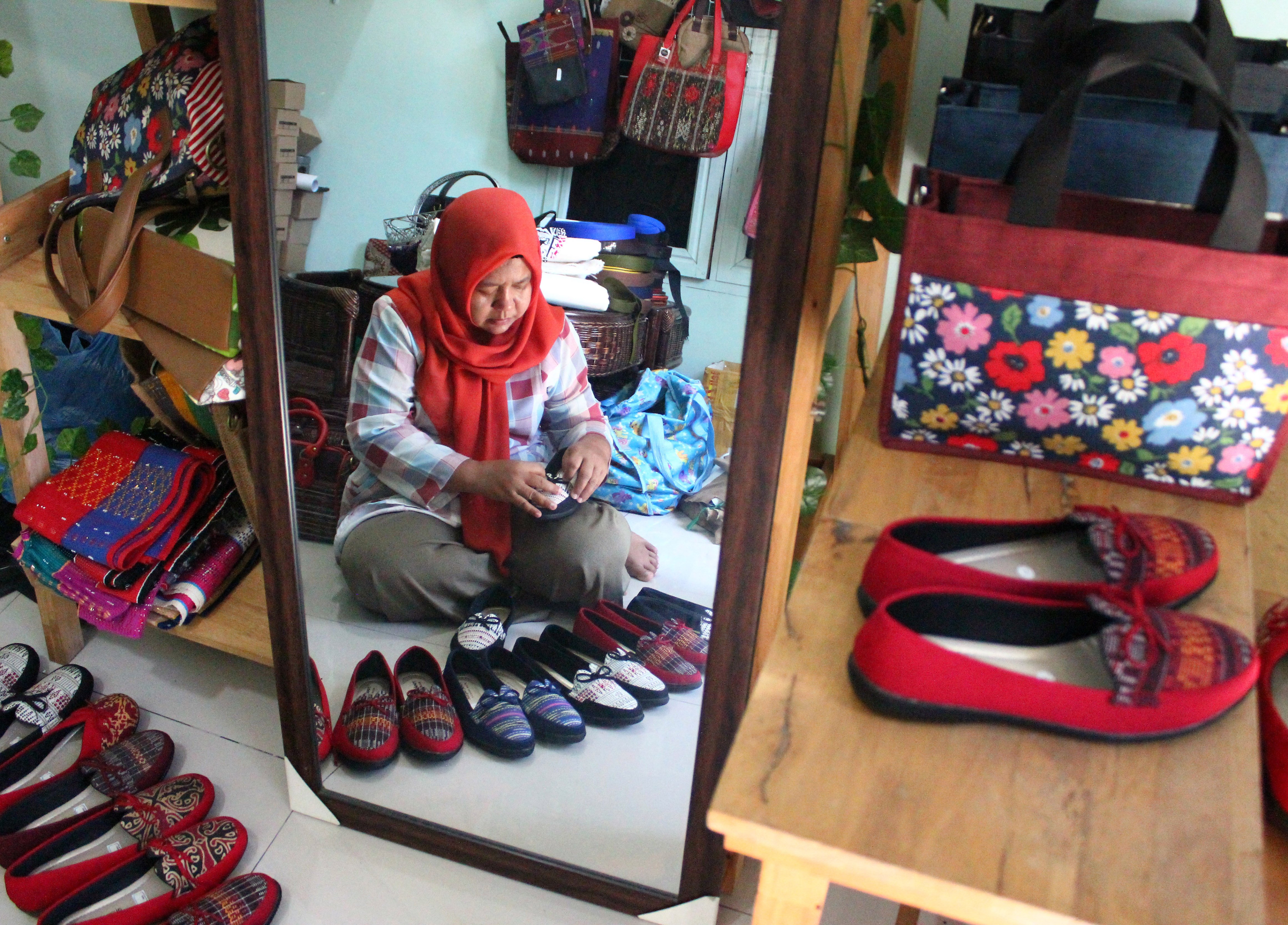 Perajin menyelesaikan pembuatan sepatu berbahan kain Ulos di rumah Nayozie, Medan, Sumatera Utara, Sabtu (15/7).