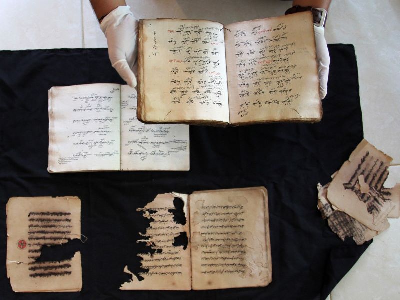 Petugas memperlihatkan kitab yang rusak dan yang masih utuh saat proses digitalisasi manuskrip di Padang, Sumatera Barat.