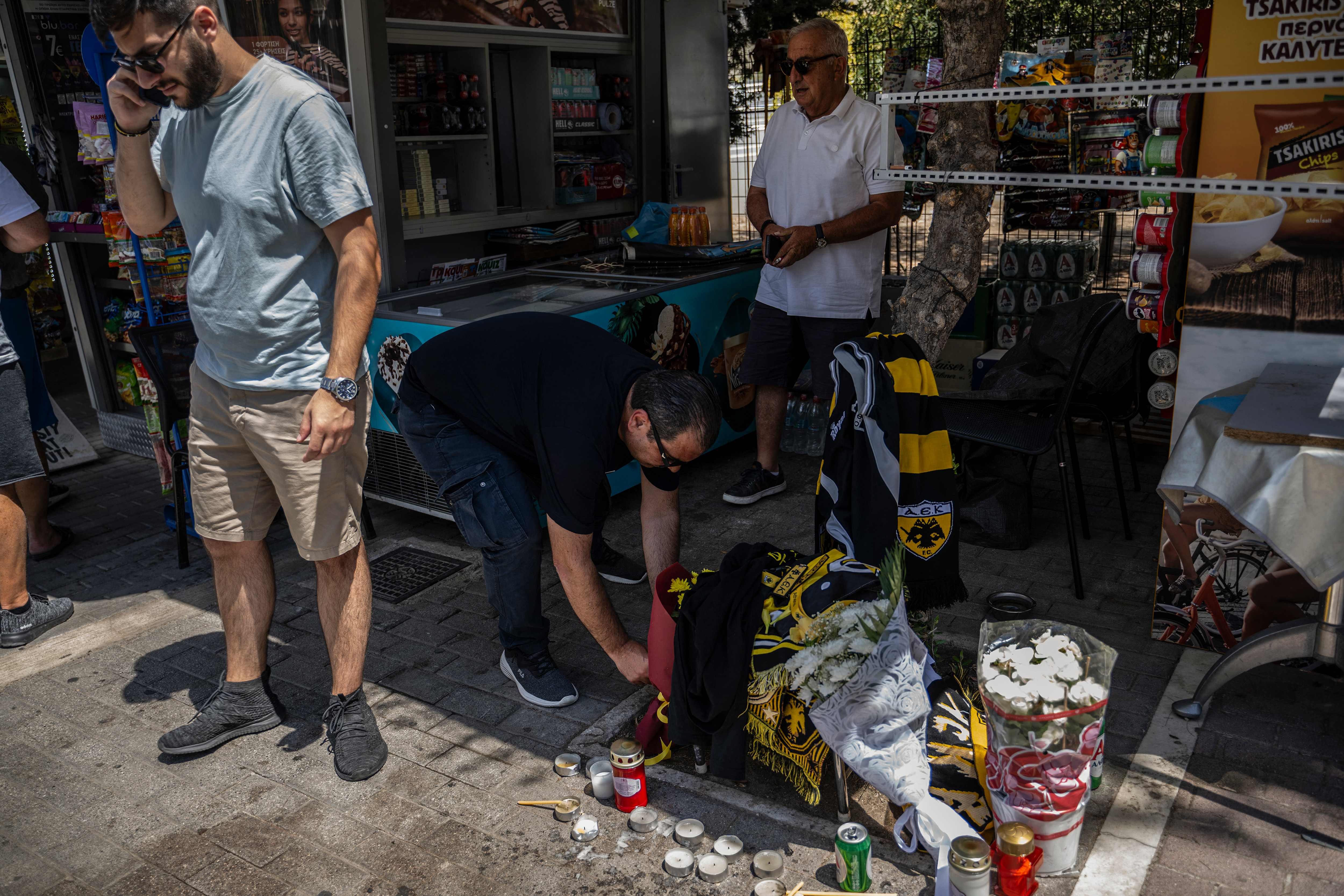 Seorang pria menyalakan lilin di lokasi tewasnya seorang pendukung AEK Athens karena ditusuk pendukung tim rival.