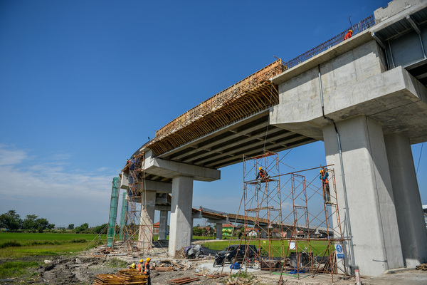 Pekerja menyelesaikan proyek pembangunan jembatan menuju Stasiun Kereta Cepat Jakarta Bandung di Tegalluar, Kabupaten Bandung.