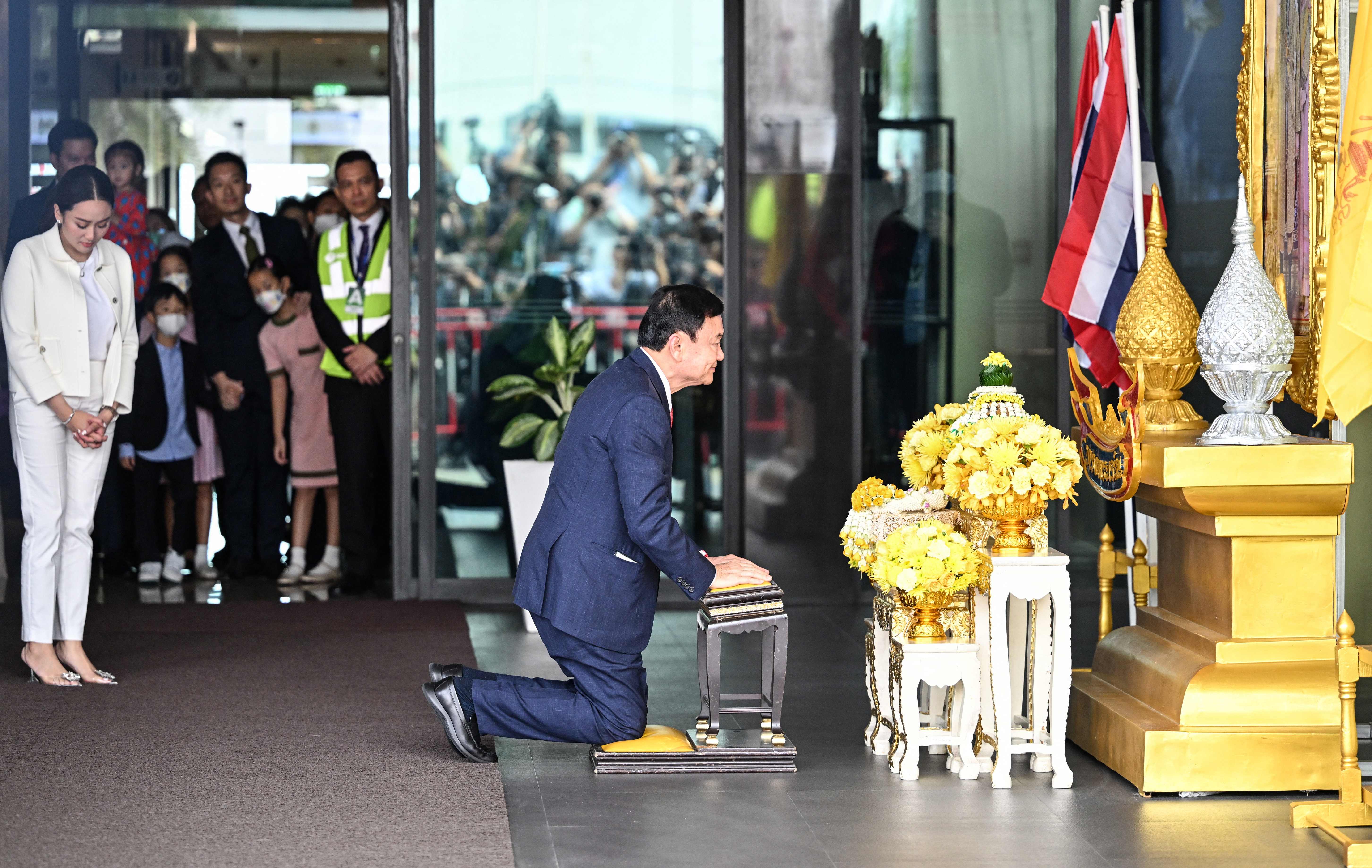 Mantan PM Thailand Thaksin Shinawatra membungkuk untuk menghormati potret raja setelah mendarat di bandara Don Mueang Bangkok.
